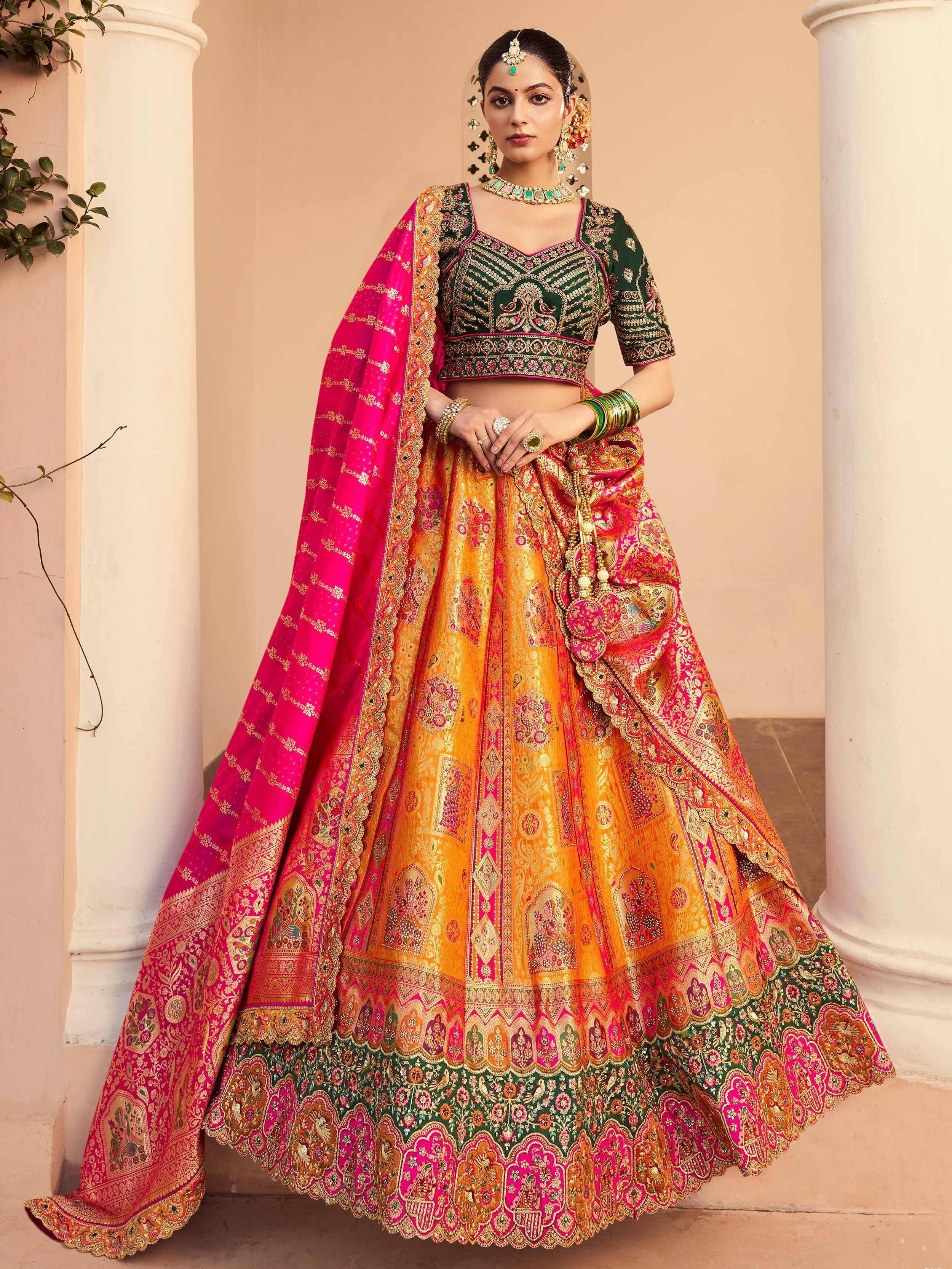 Designer lehenga choli in vibrant pink, green, and gold with intricate embroidery and dupatta