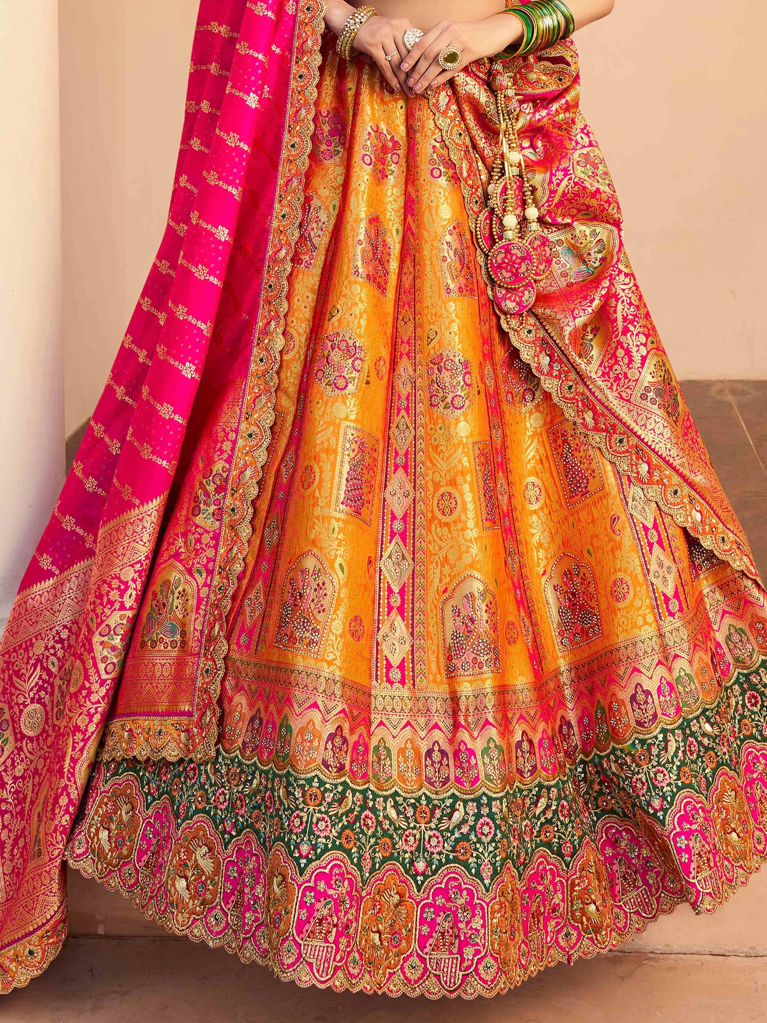 Vibrant orange and pink designer lehenga choli with intricate gold embroidery and traditional Indian motifs