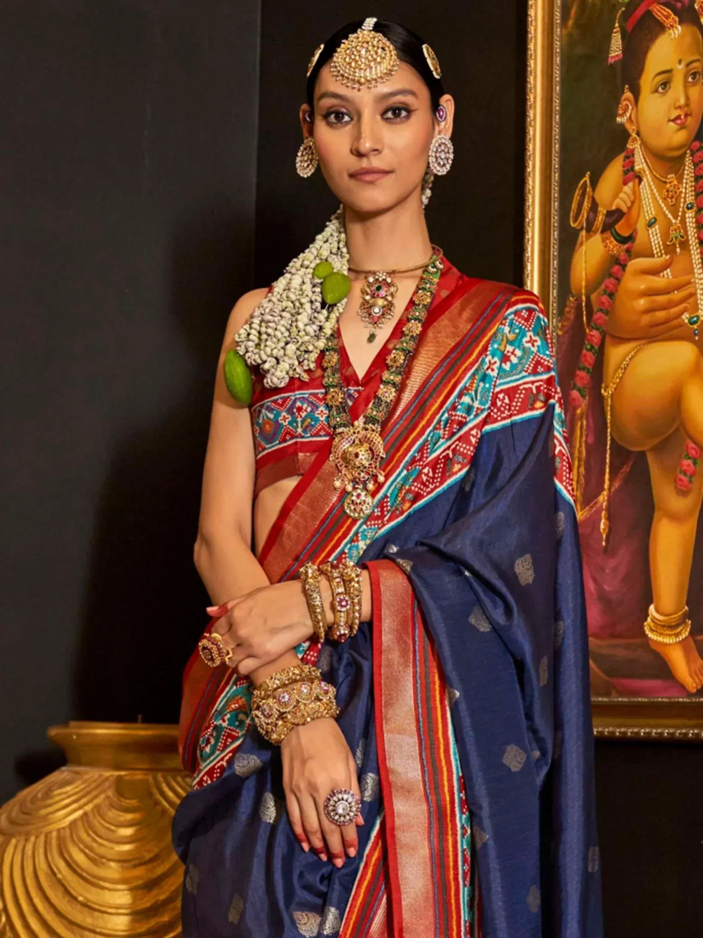 Woman in traditional Indian saree with temple jewelry and floral garland, ethnic wear styling