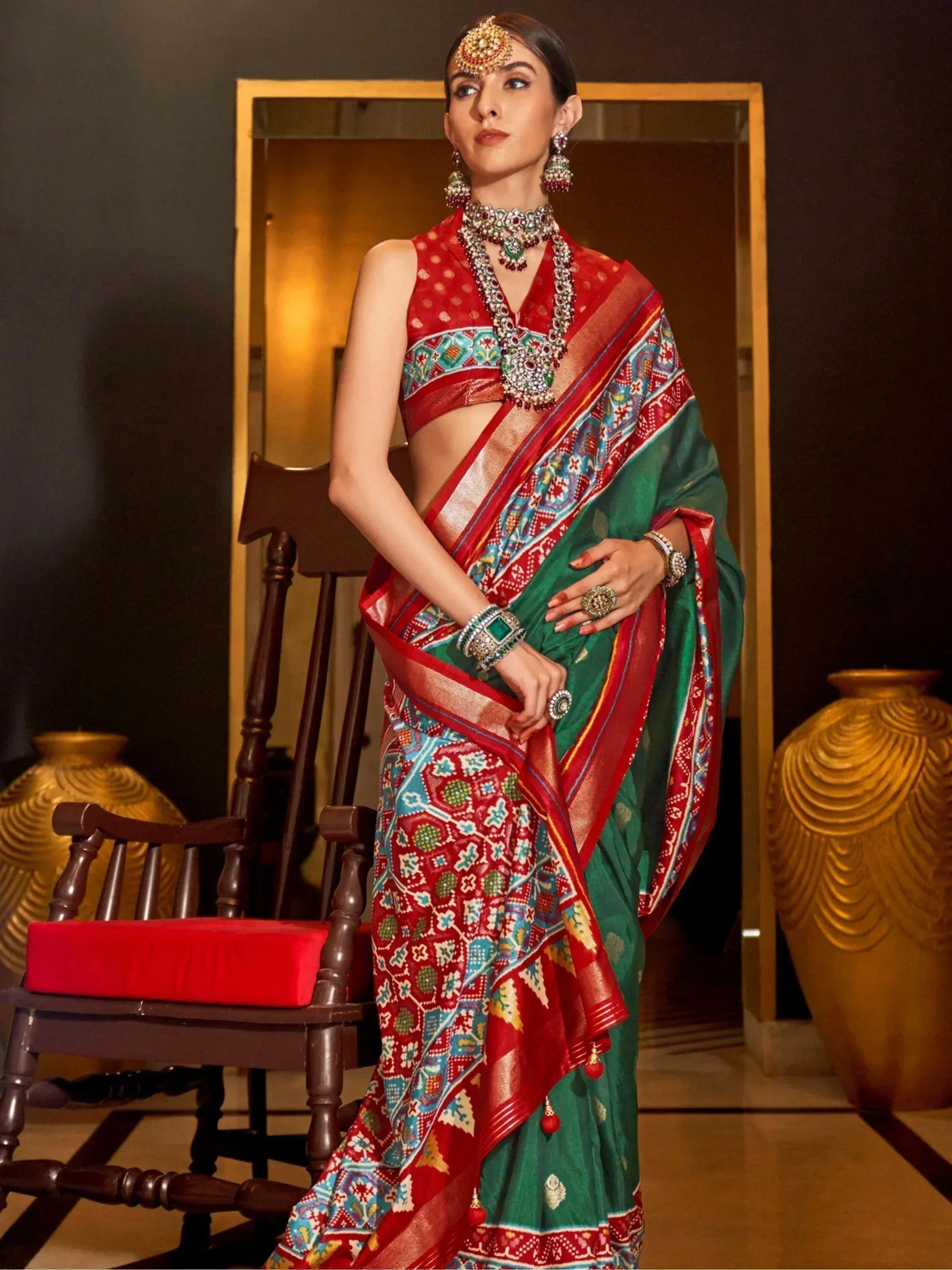 Woman in vibrant red and green printed saree with ethnic jewelry, styled for festive occasions
