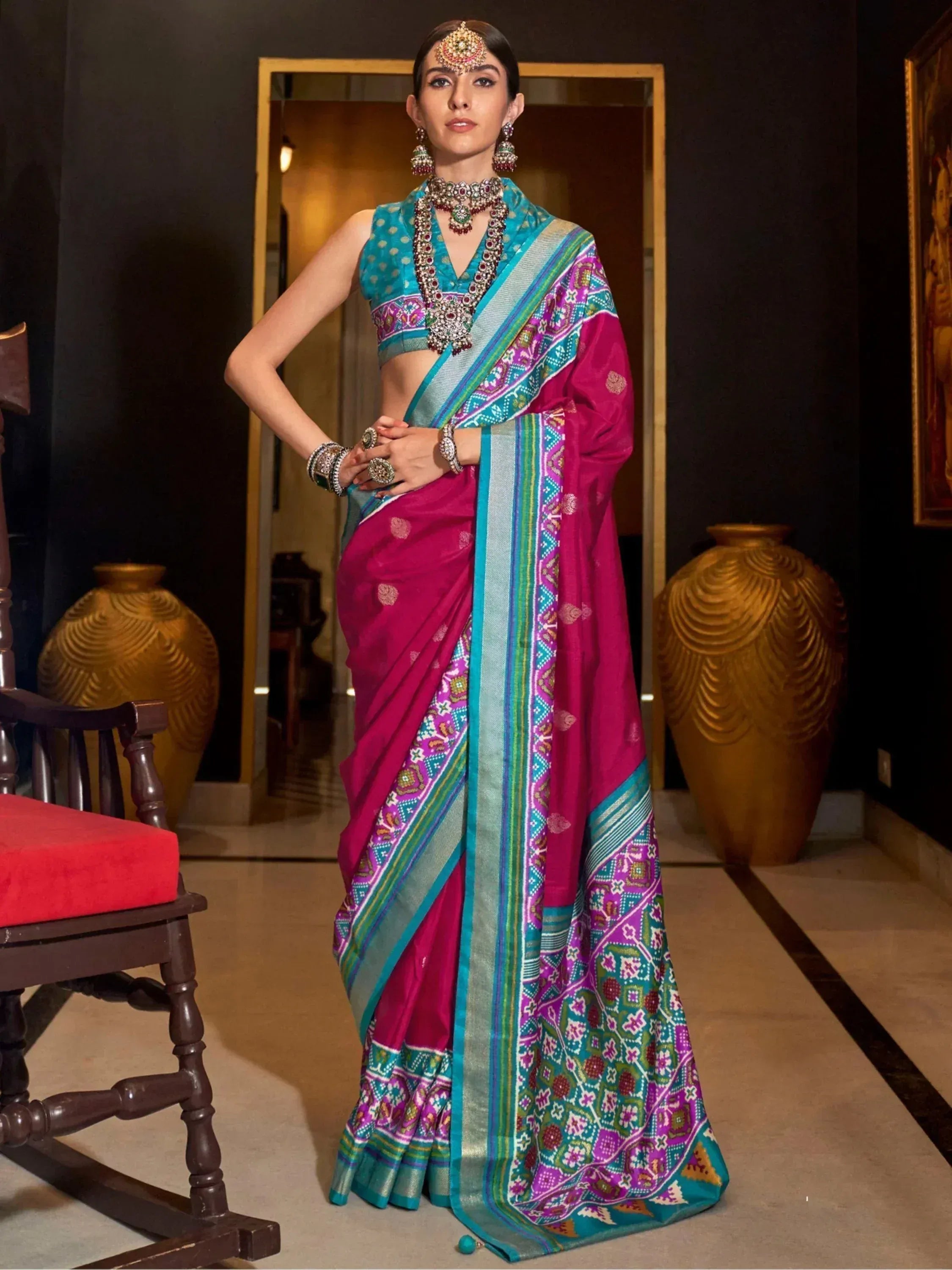 Woman in vibrant pink and teal designer saree with intricate embroidery, traditional Indian ethnic wear