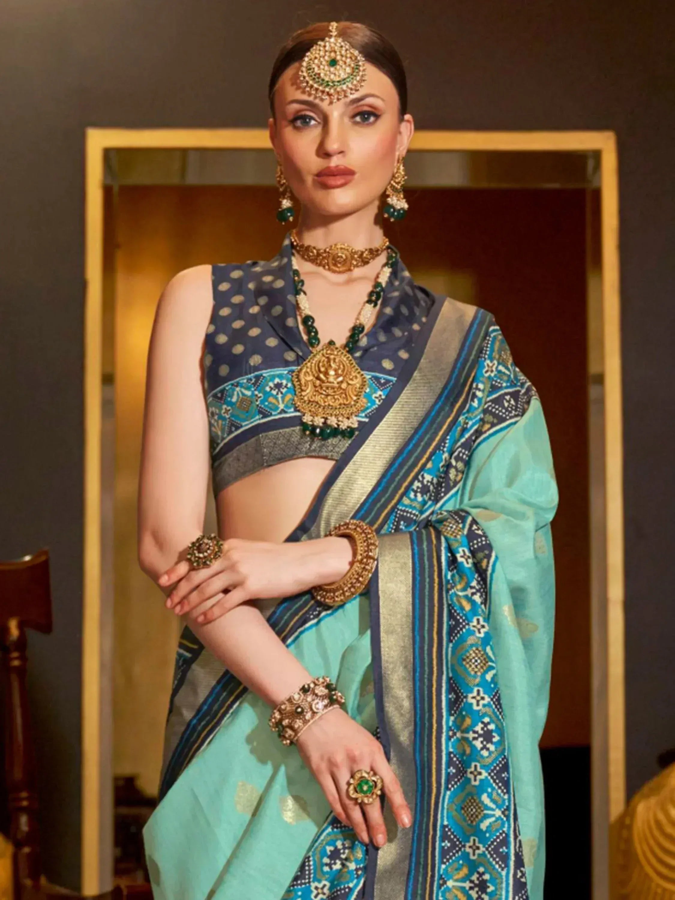Woman in elegant blue and teal printed saree with gold jewelry, traditional Indian ethnic wear