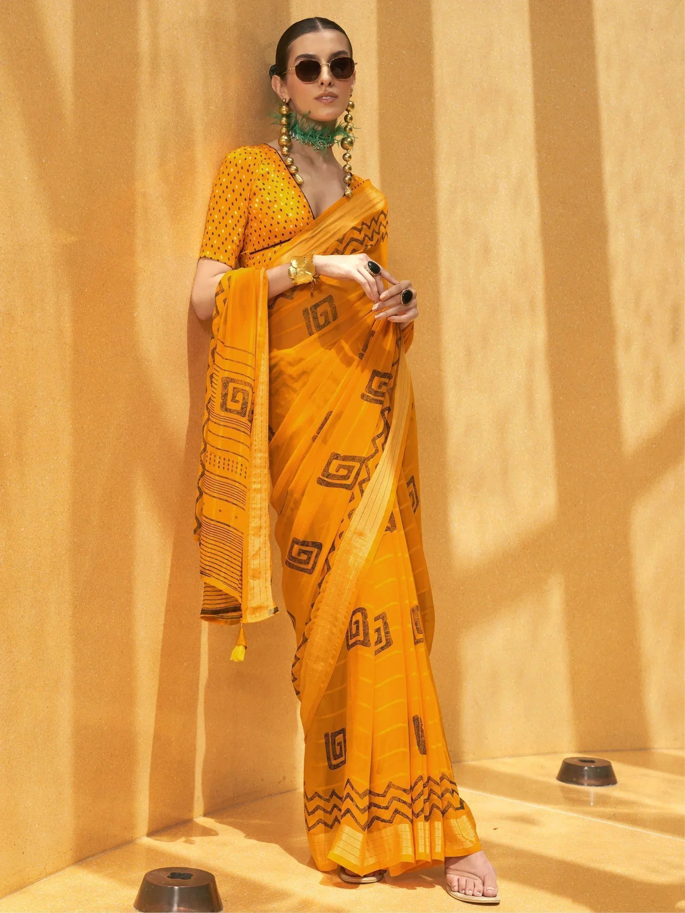 Vibrant yellow saree with black geometric print, paired with matching blouse, styled for ethnic wear.
