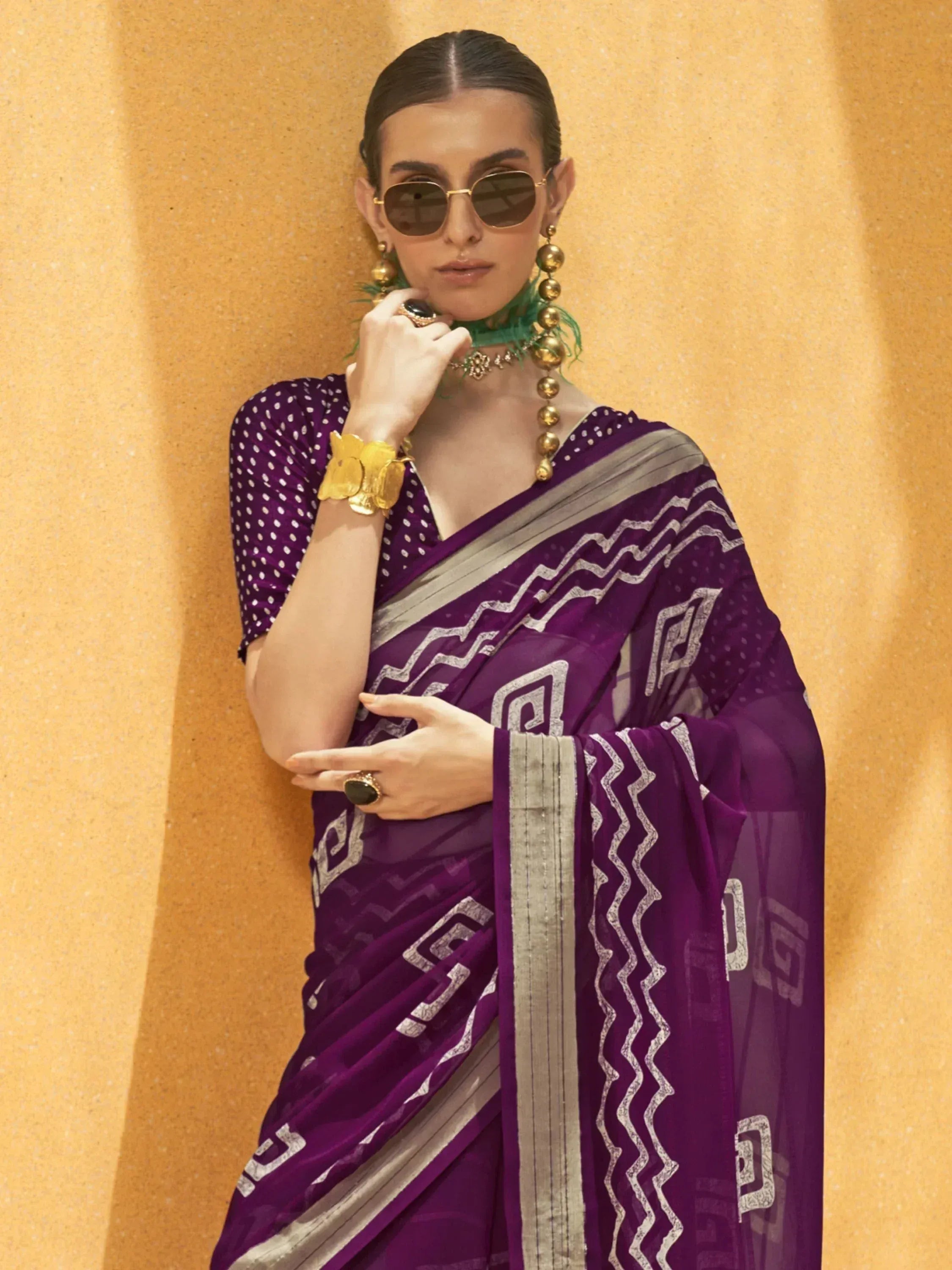 Purple ethnic saree with geometric print and gold jewelry, styled with sunglasses for modern Indian fashion