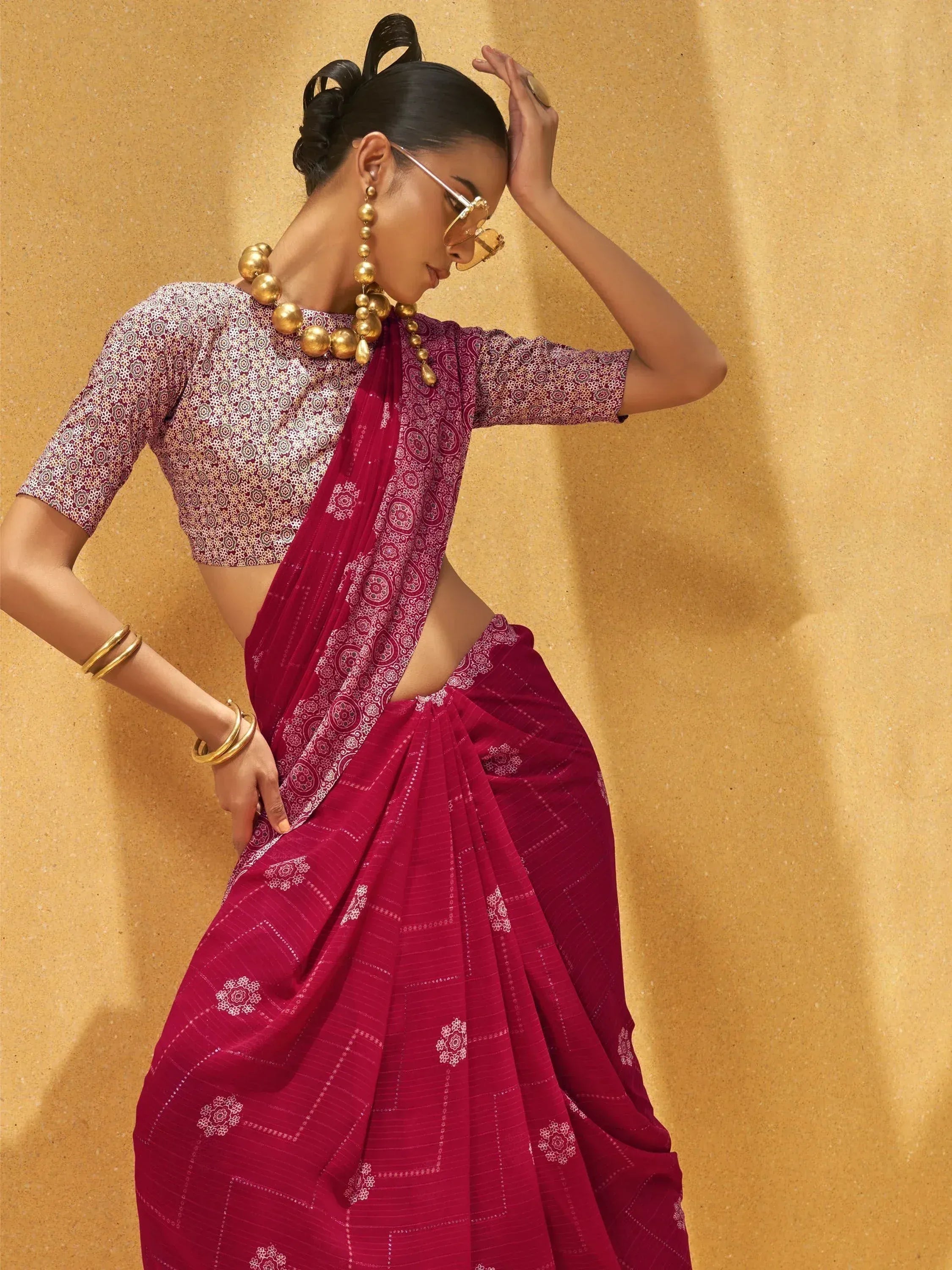 Woman in maroon printed saree with gold jewelry, stylish ethnic wear for Indian occasions