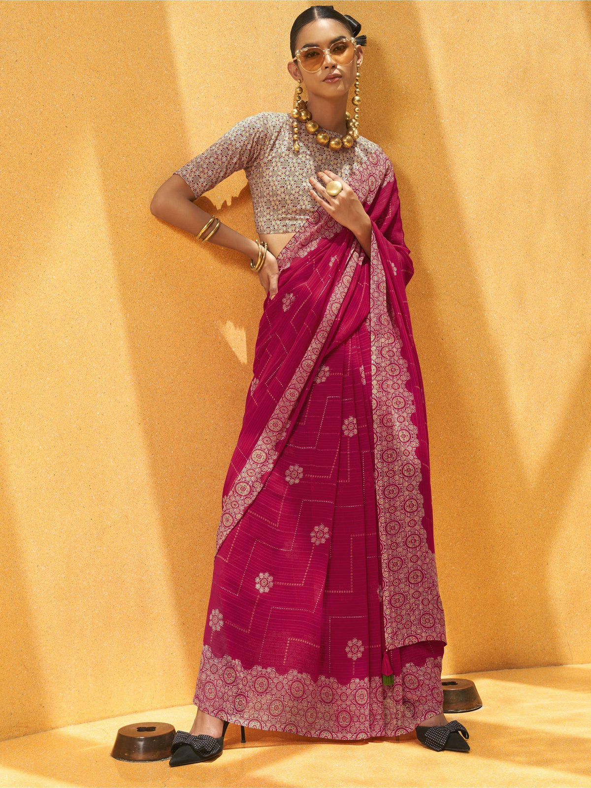 Stylish magenta saree with gold print, paired with matching blouse and gold jewelry, perfect for ethnic occasions.