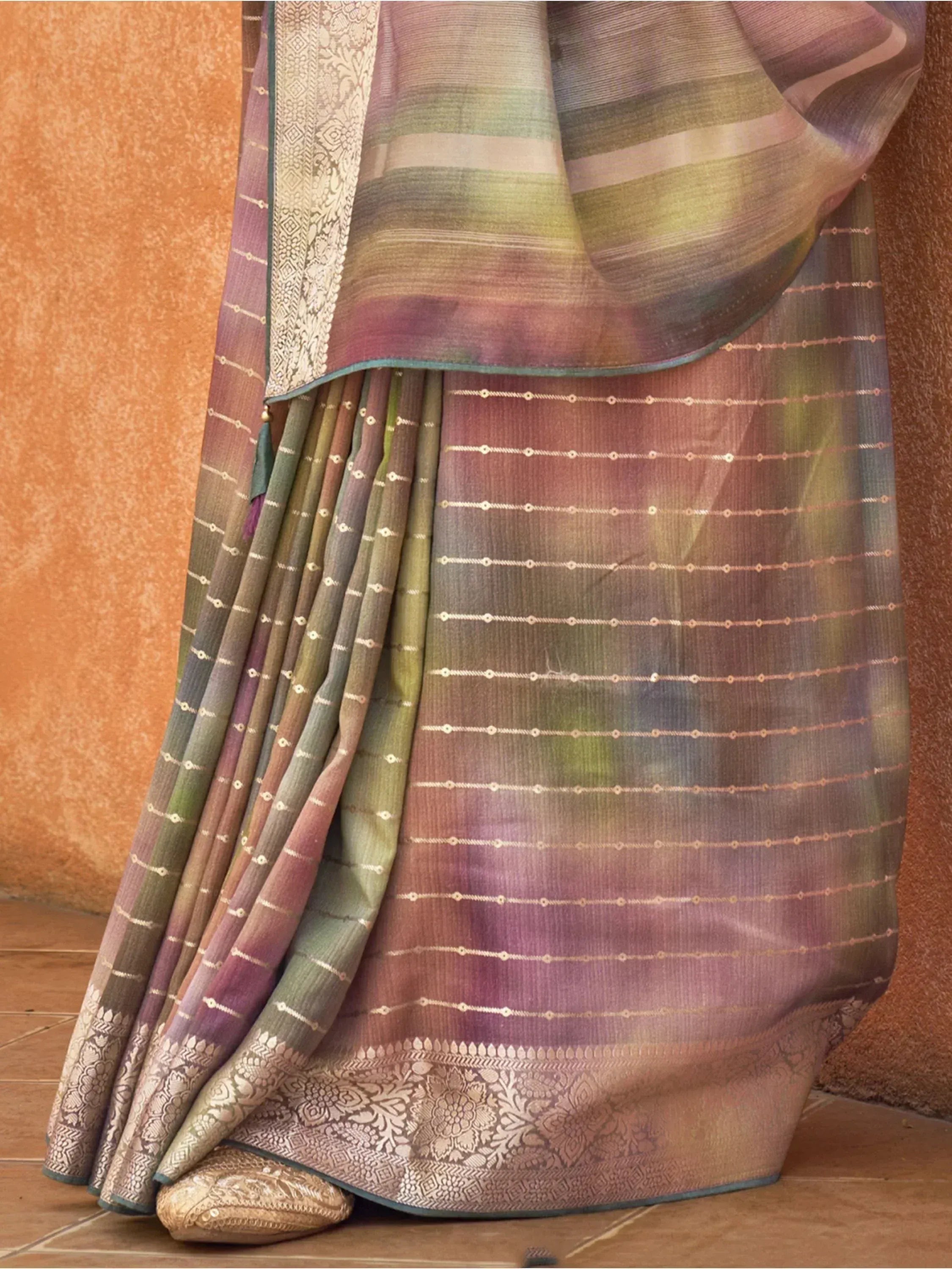 Elegant Indian saree with ombre green-purple hues, gold zari stripes, and floral border, styled with traditional footwear.