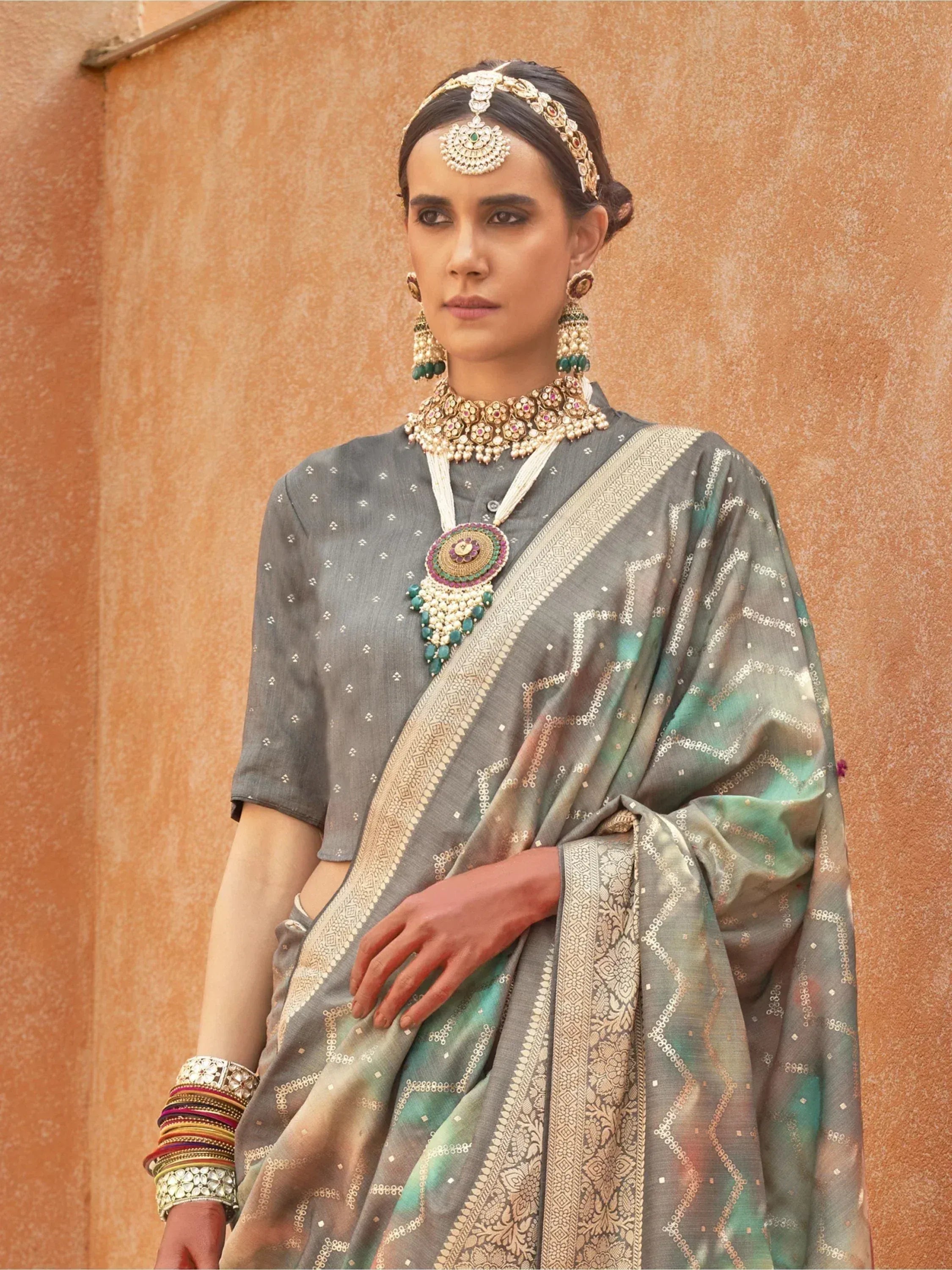 Grey and green ethnic saree with gold embroidery, paired with traditional Indian jewelry for festive occasions.