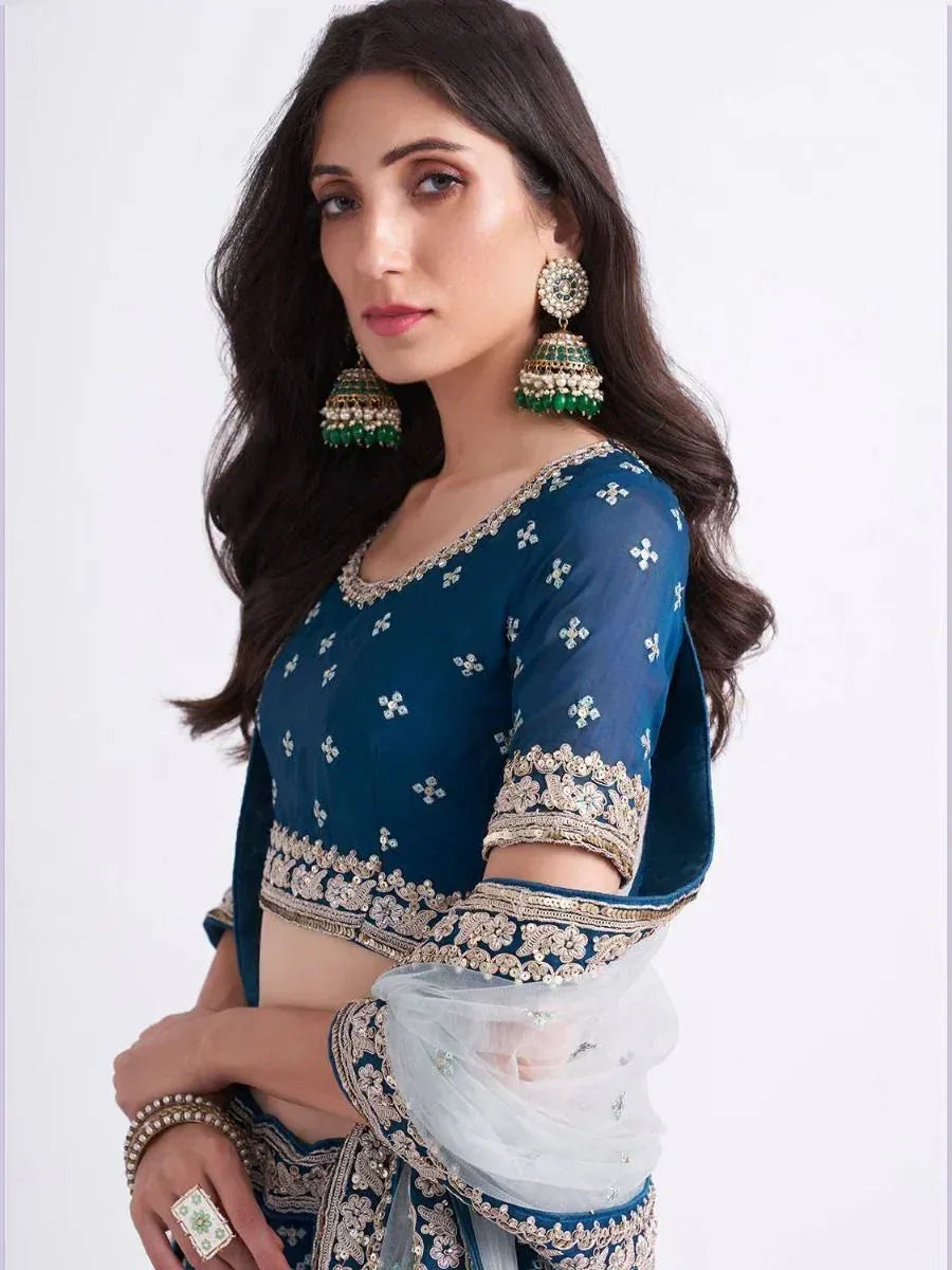 Blue embroidered lehenga choli with gold detailing and green jhumka earrings, Indian ethnic wear