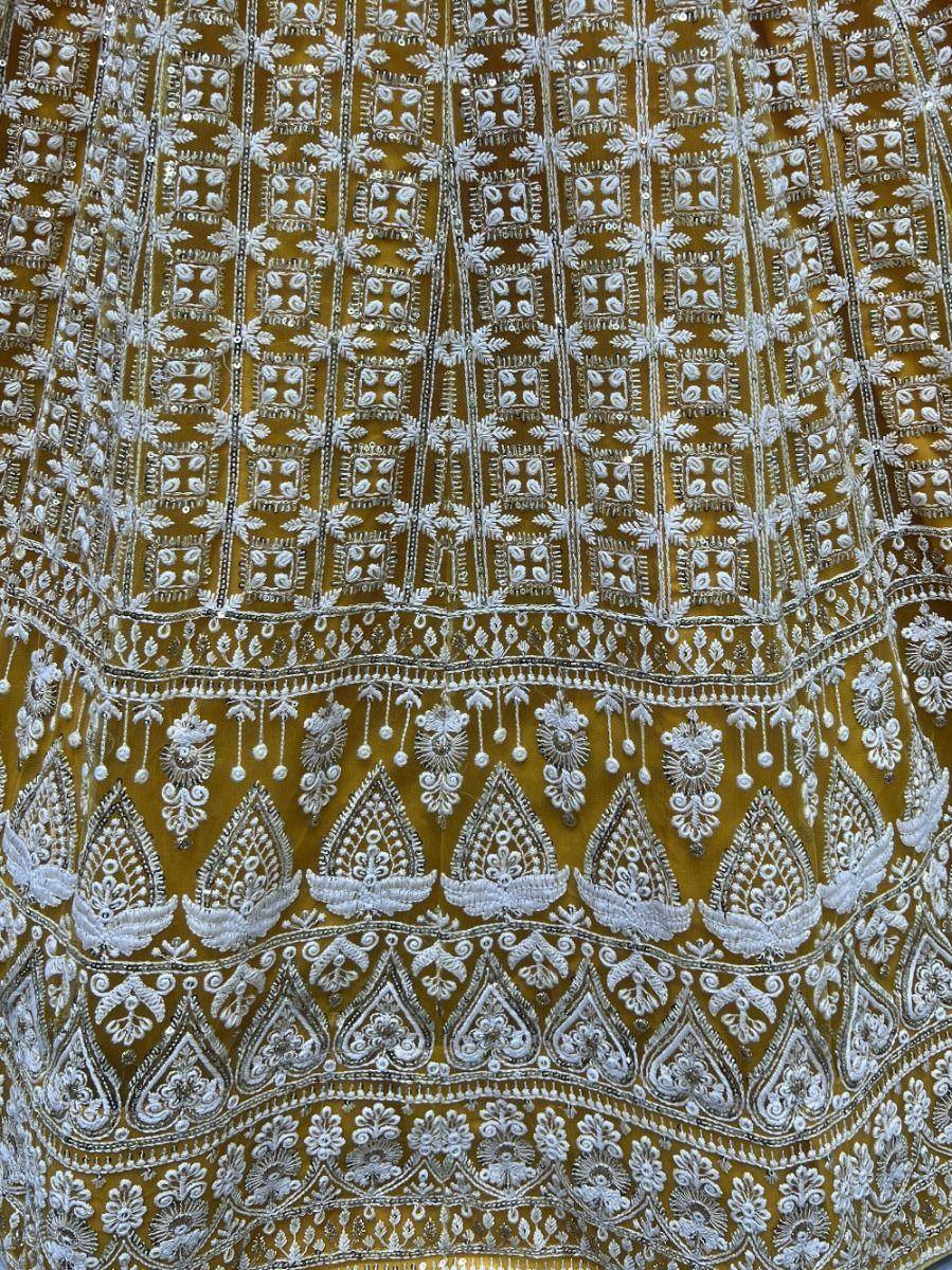 Golden ethnic lehenga with intricate white embroidery and detailed border patterns