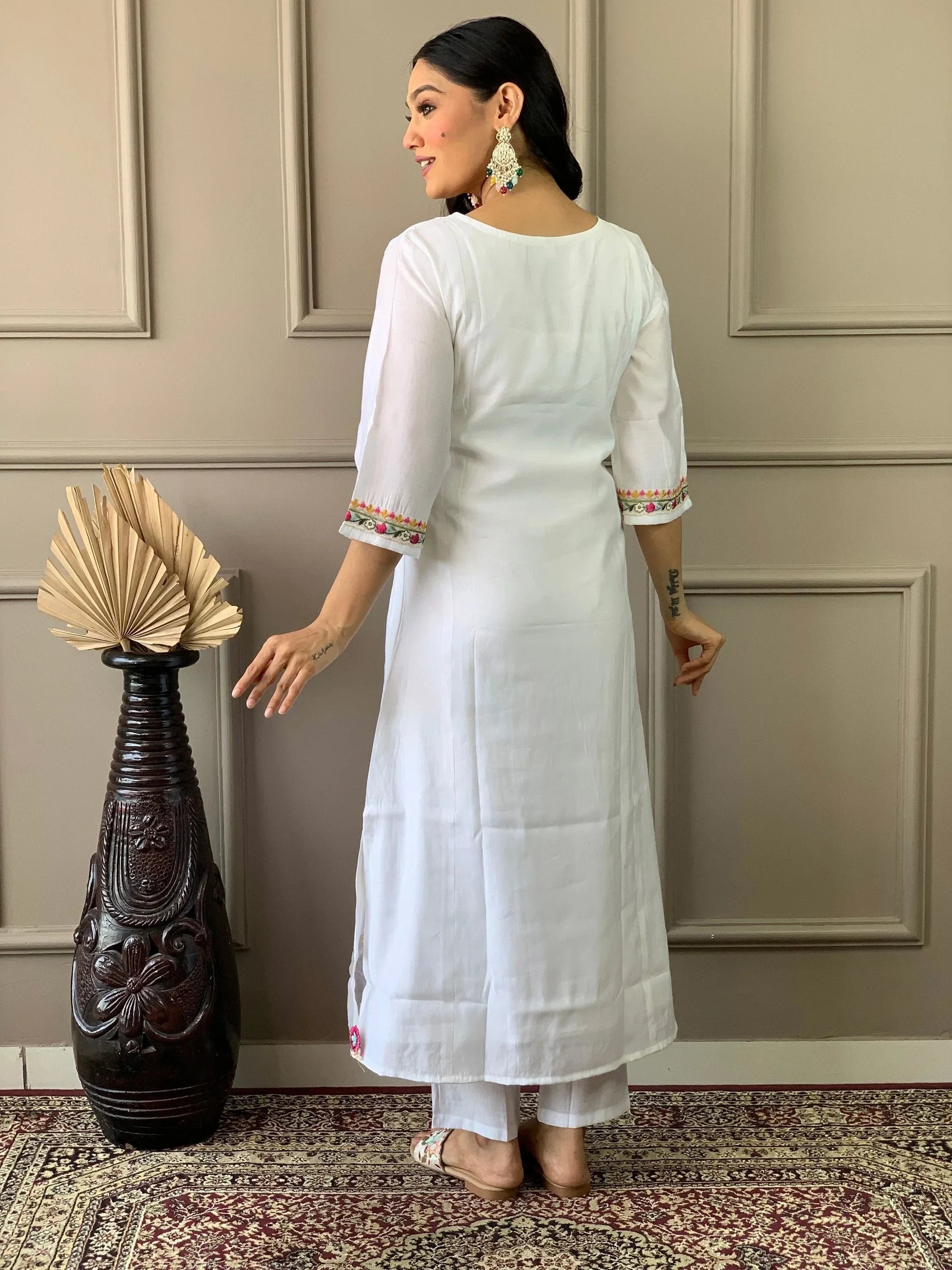 Woman wearing white embroidered kurti and pants, standing indoors, Indian ethnic outfit