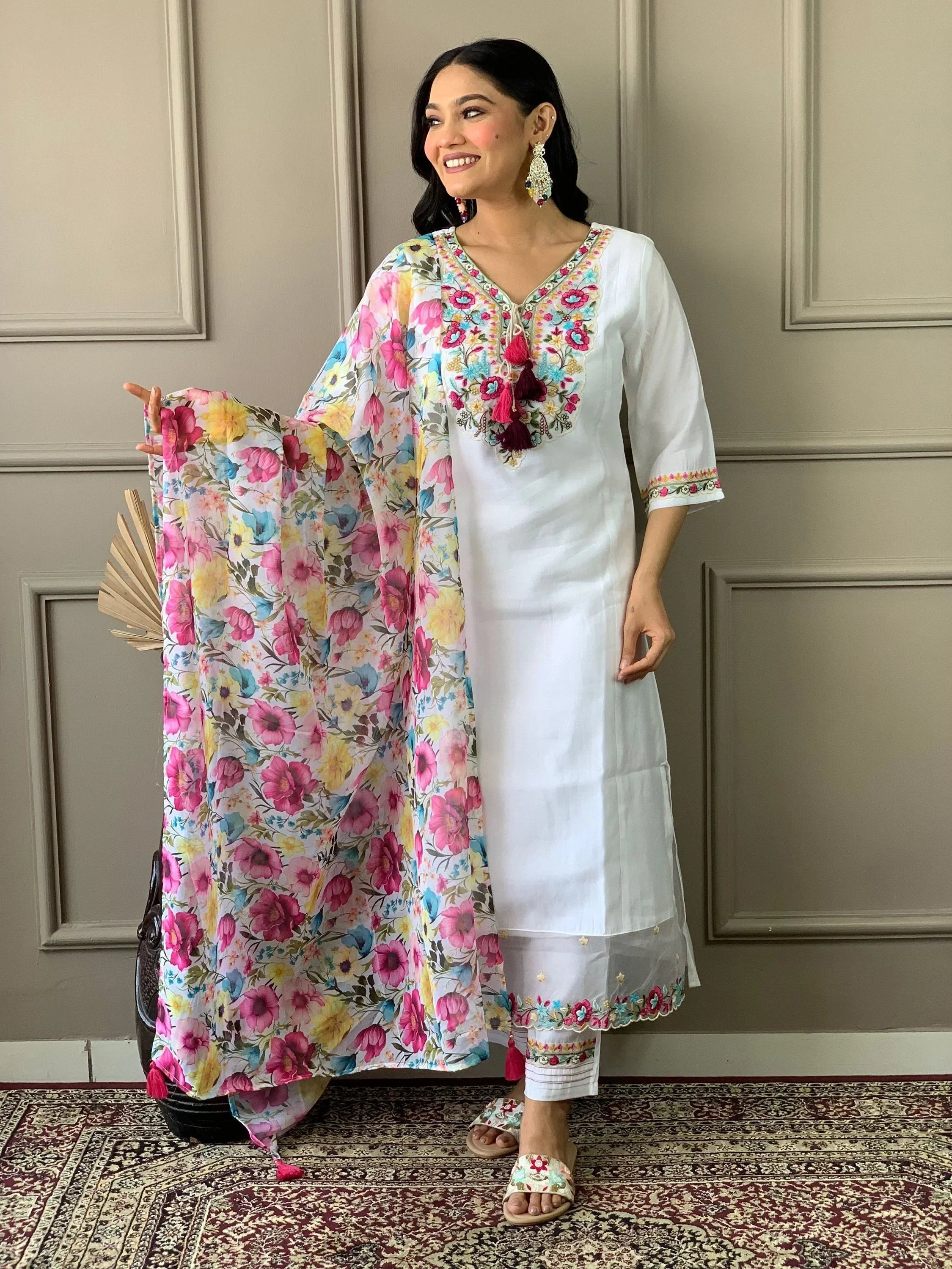 Woman wearing white embroidered salwar kameez with floral dupatta and statement earrings