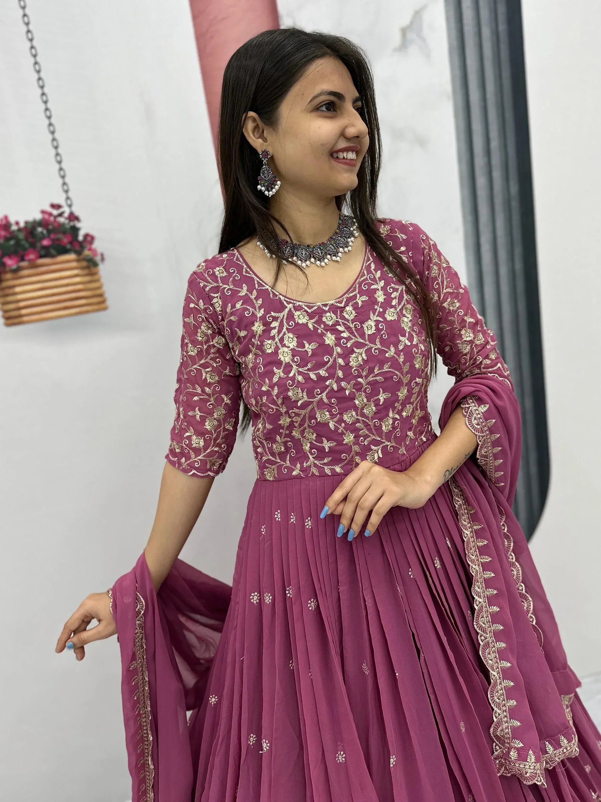 Woman in maroon embroidered Indian ethnic wear with gold floral details, perfect for festive occasions.