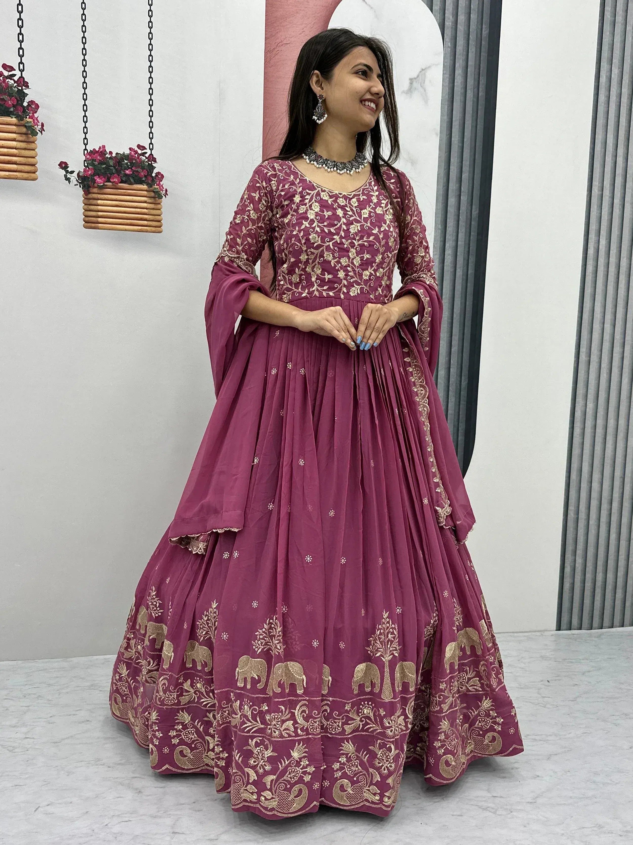 Woman in maroon ethnic gown with gold elephant embroidery, perfect for Indian occasions and festivals
