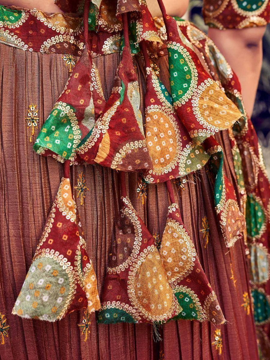 Ethnic patchwork lehenga with embroidered tassels and pleated skirt in maroon, green, and gold tones