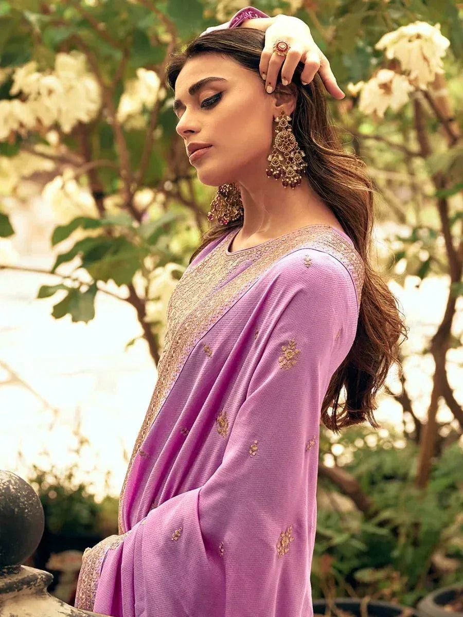Purple embroidered ethnic gown with gold detailing, styled with jhumka earrings for festive occasions