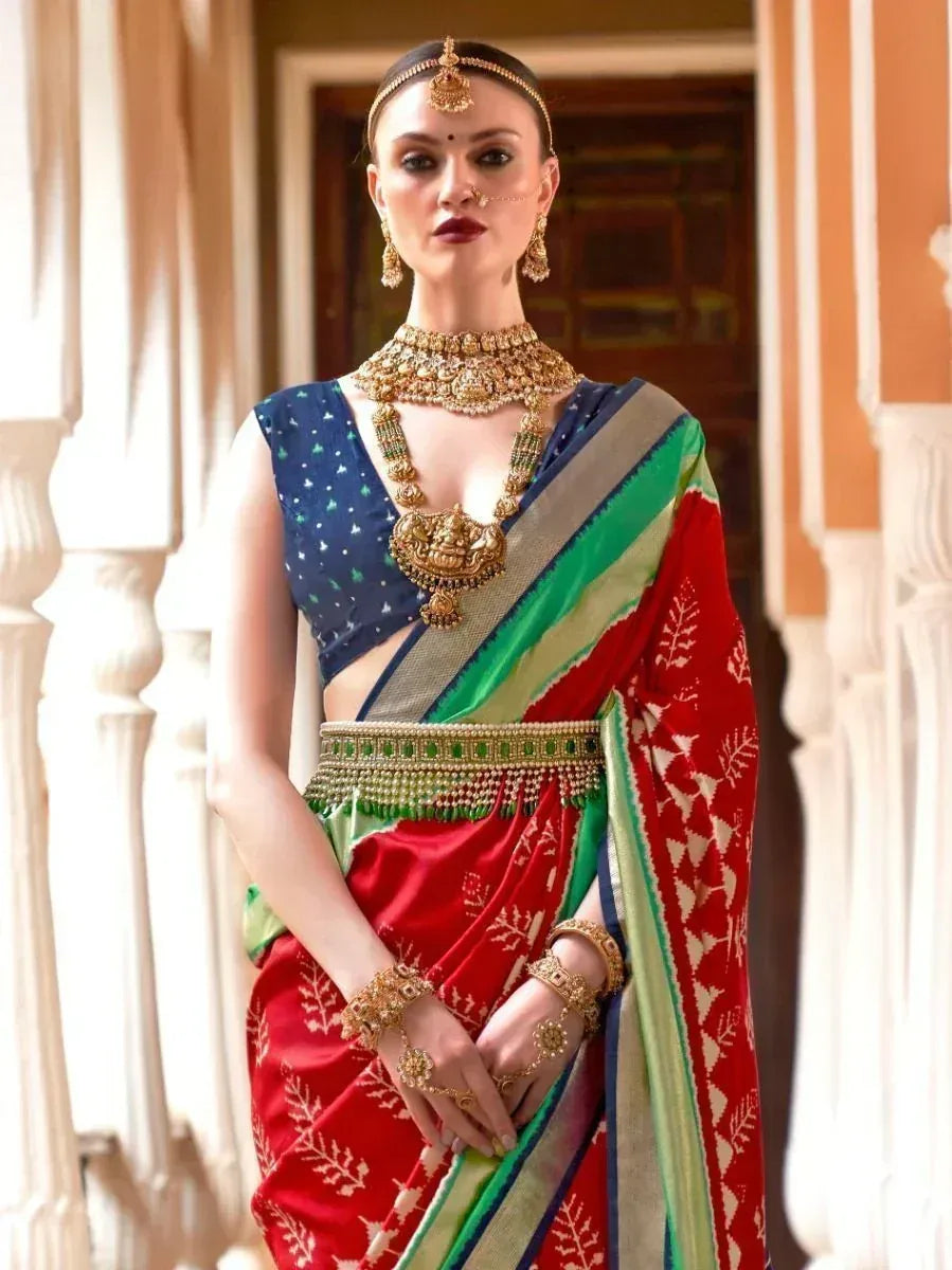 Woman in red and blue designer saree with gold jewelry, ethnic Indian wear