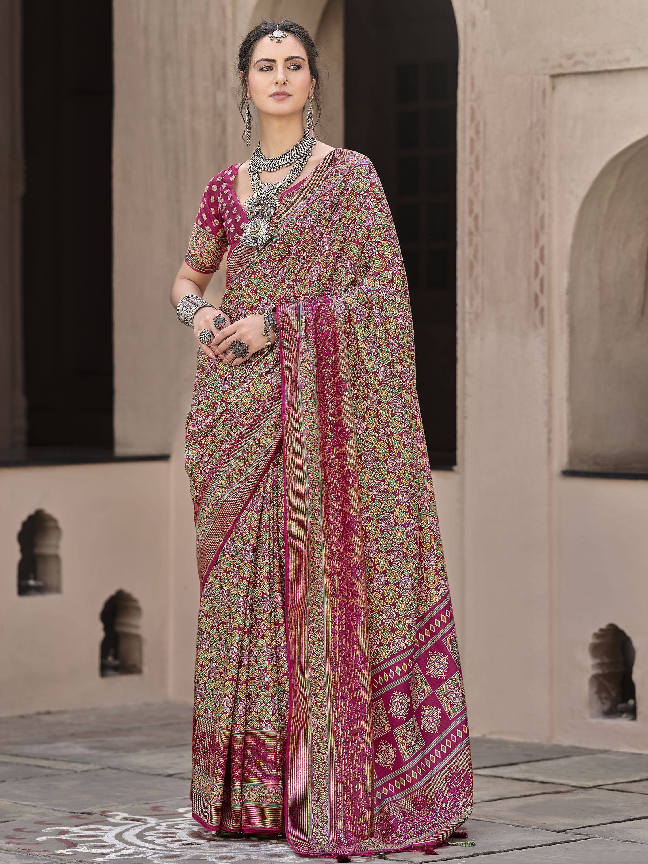 Woman in maroon ethnic saree with gold green print, traditional jewelry, standing at heritage building