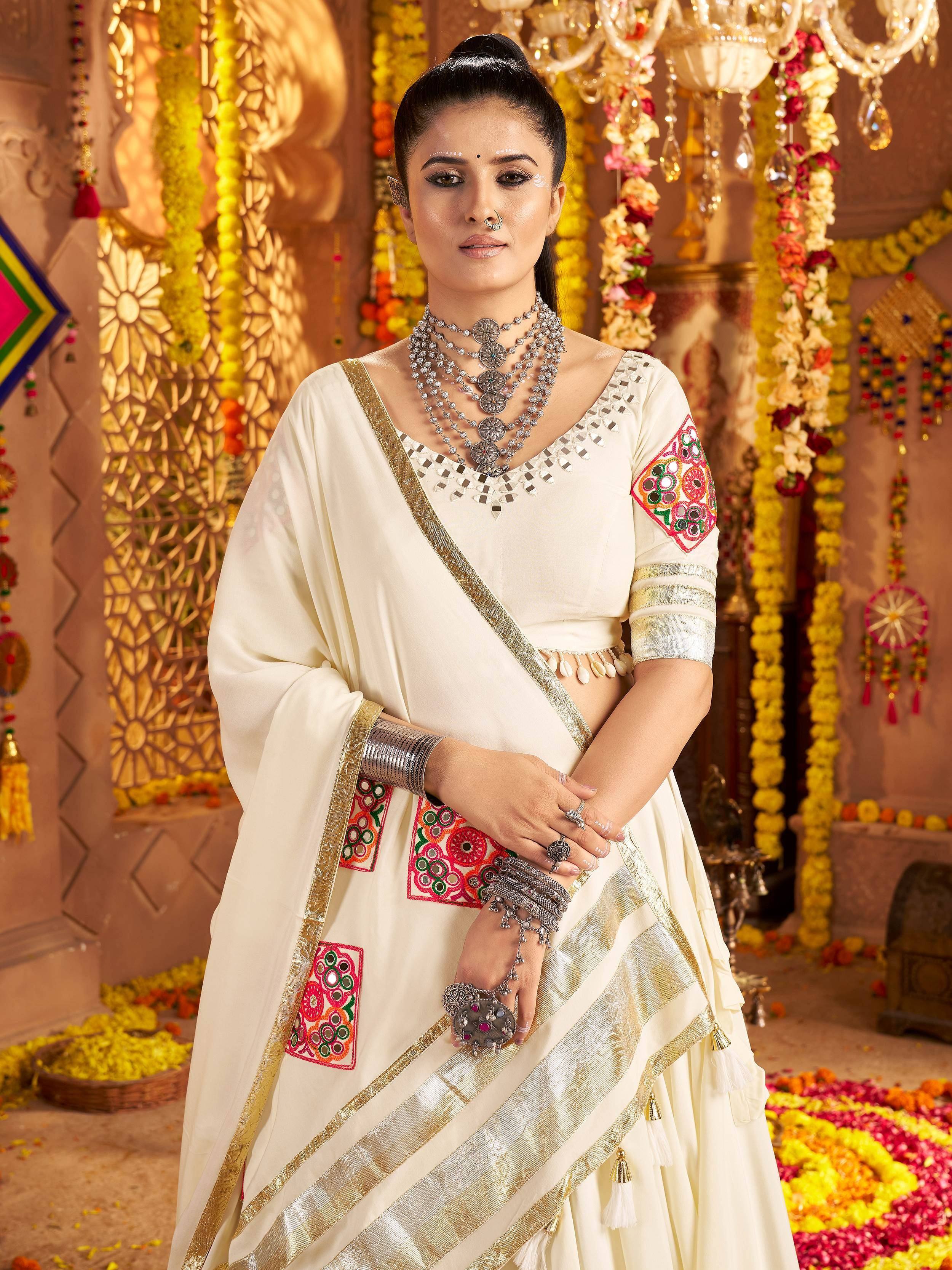 Cream embroidered lehenga choli with mirror work, gold border, and traditional Indian jewelry for festive occasions