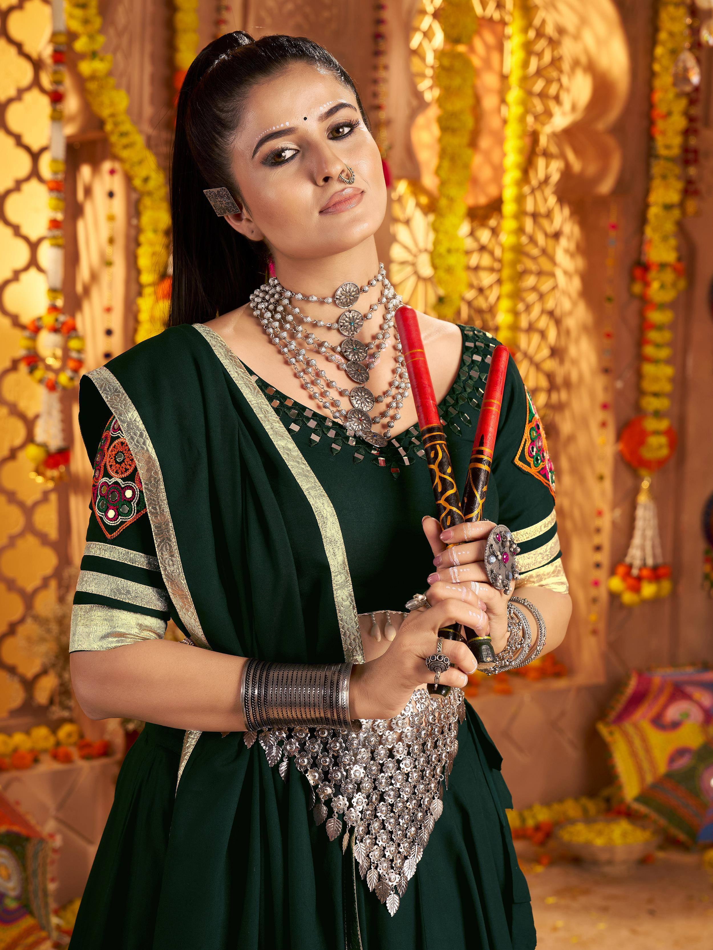 Woman in green ethnic Indian dress with mirror work, silver jewelry, and traditional accessories for festive occasions.