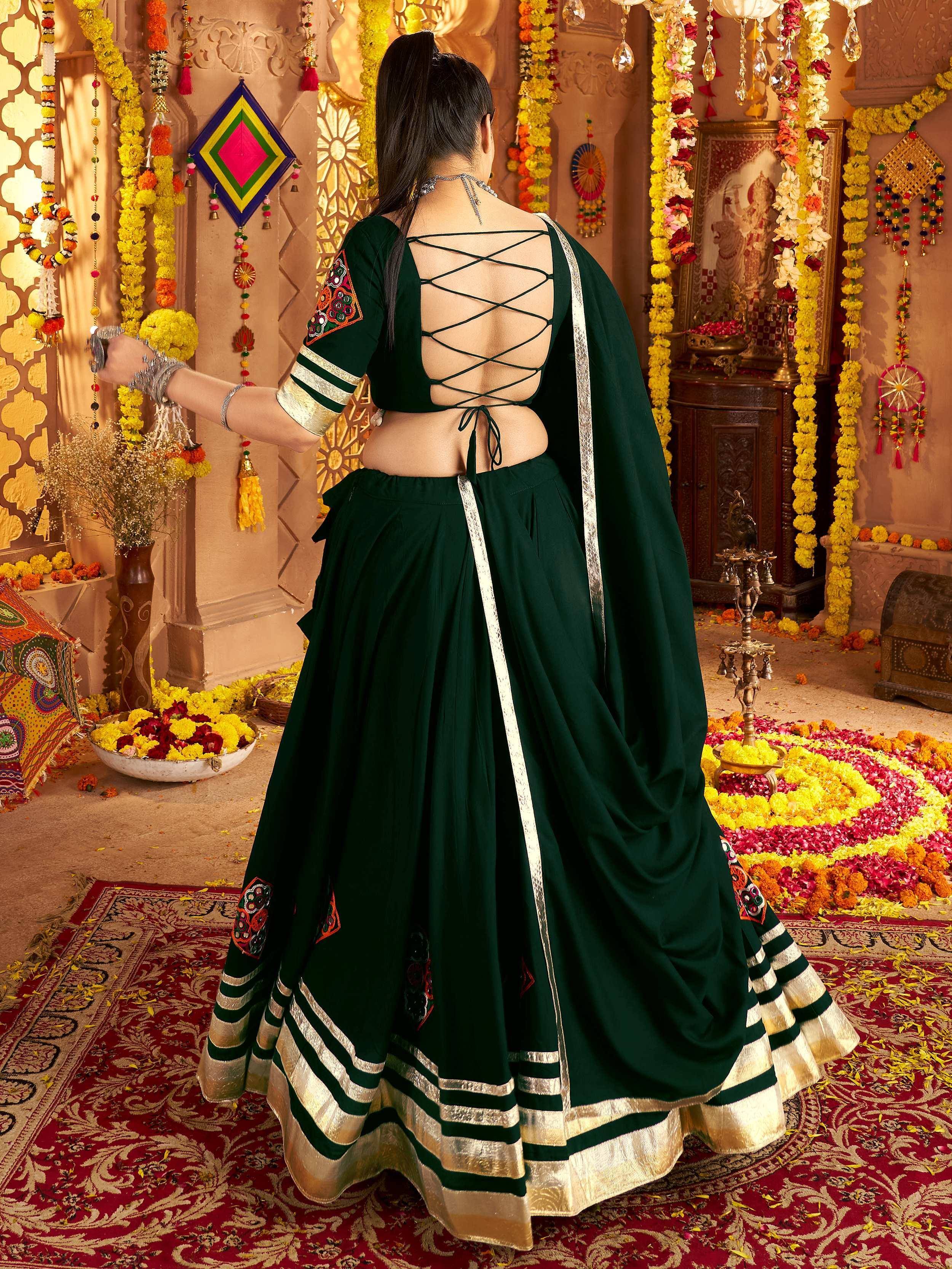 Emerald green designer lehenga choli with back crisscross detail, floral embroidery, and gold trim, perfect for Indian festivals.