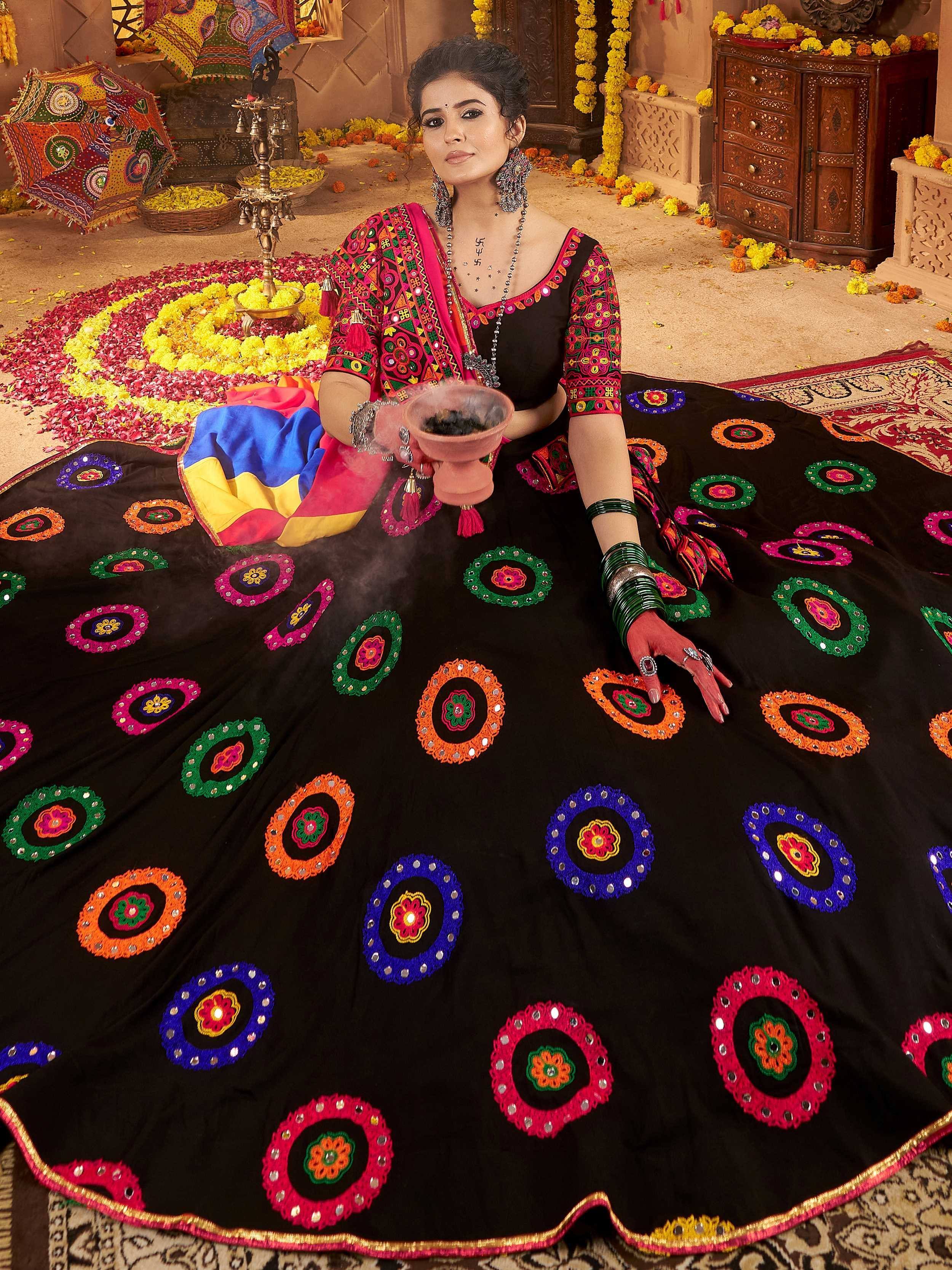 Woman in vibrant black embroidered lehenga choli with colorful mirror work, traditional Indian ethnic wear