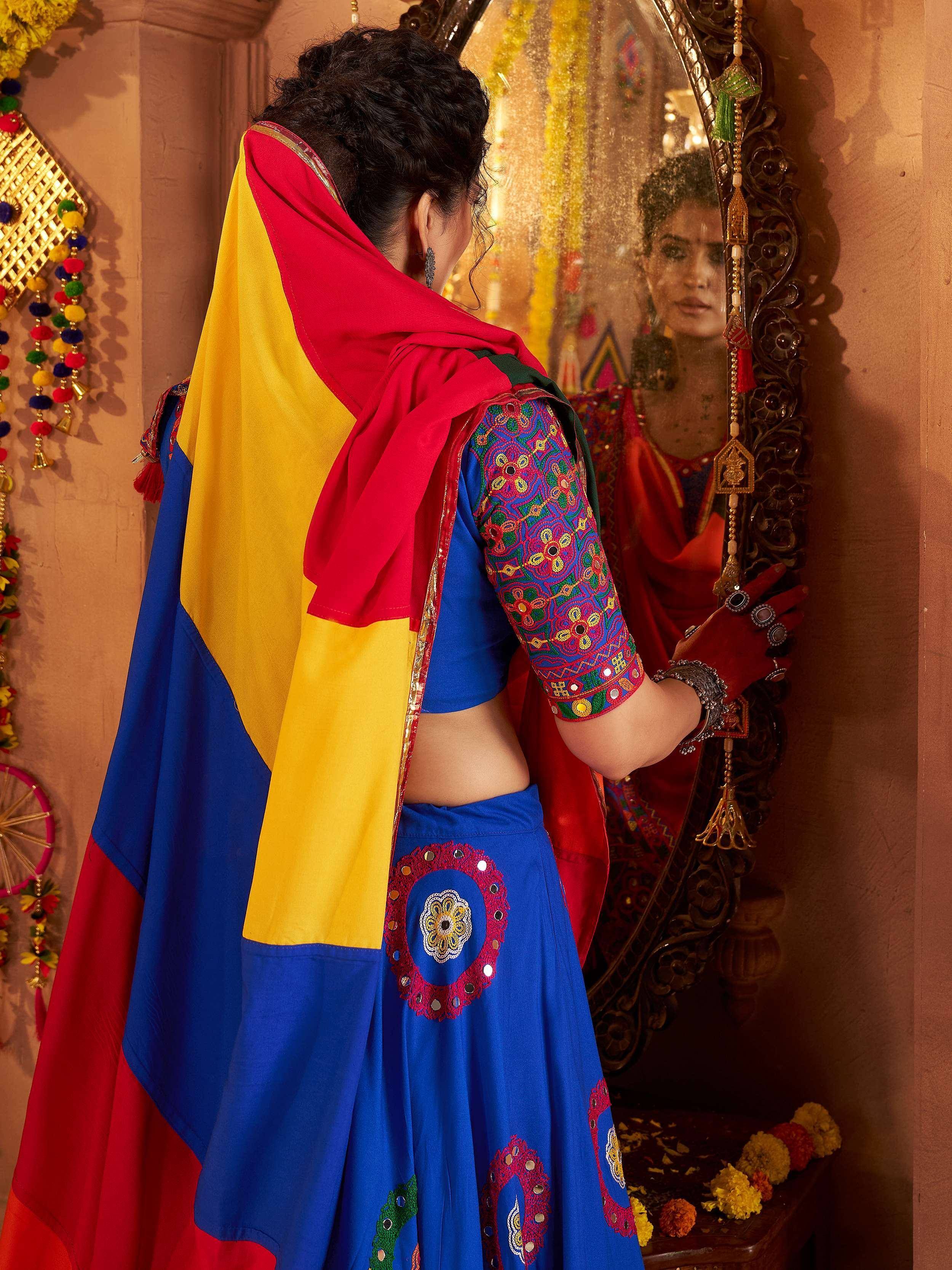 Woman in vibrant blue embroidered lehenga choli with red yellow dupatta, traditional Indian ethnic wear