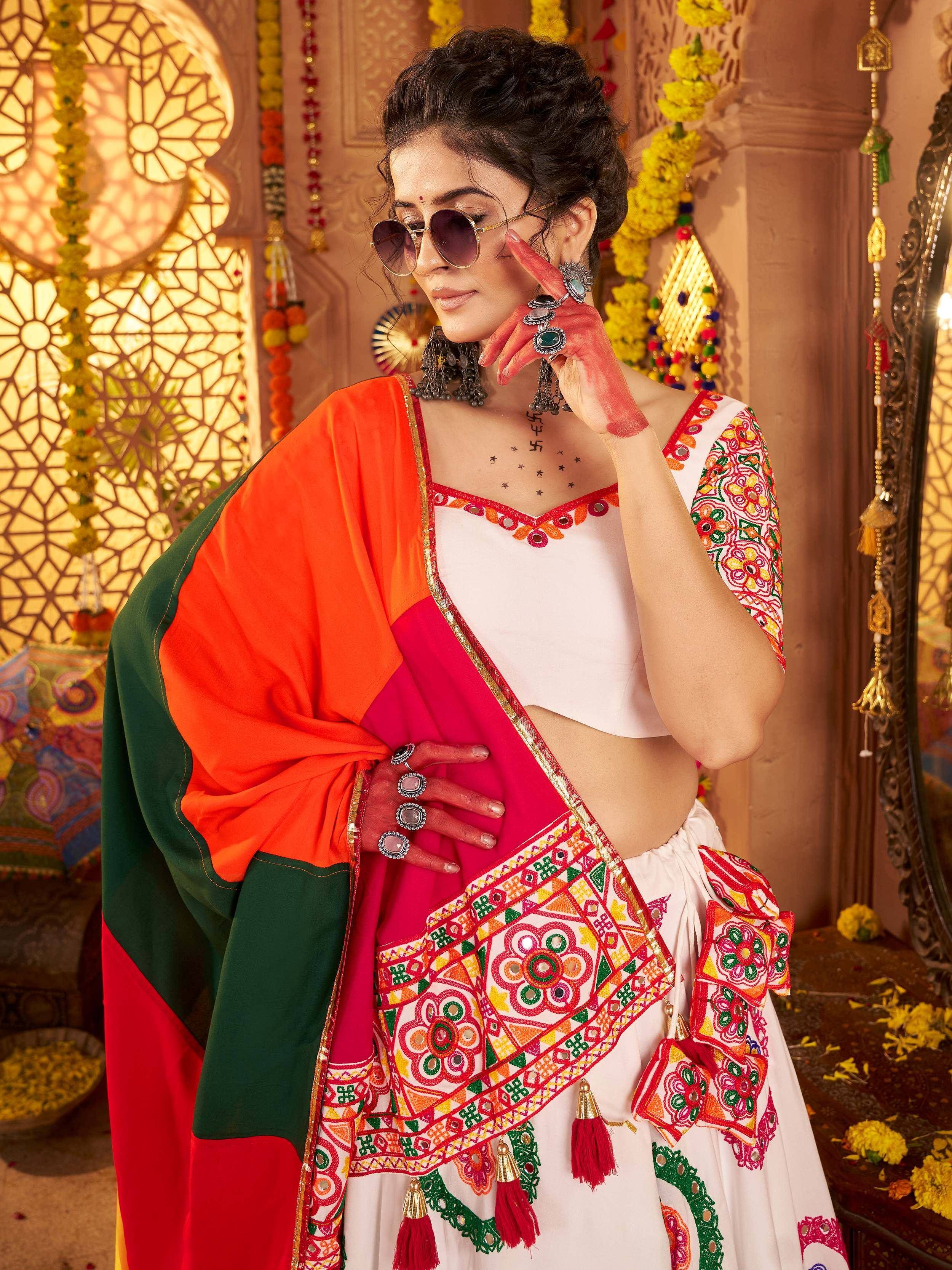 Woman in vibrant Indian ethnic wear with mirror work, floral embroidery, and colorful dupatta, styled for festive occasions.