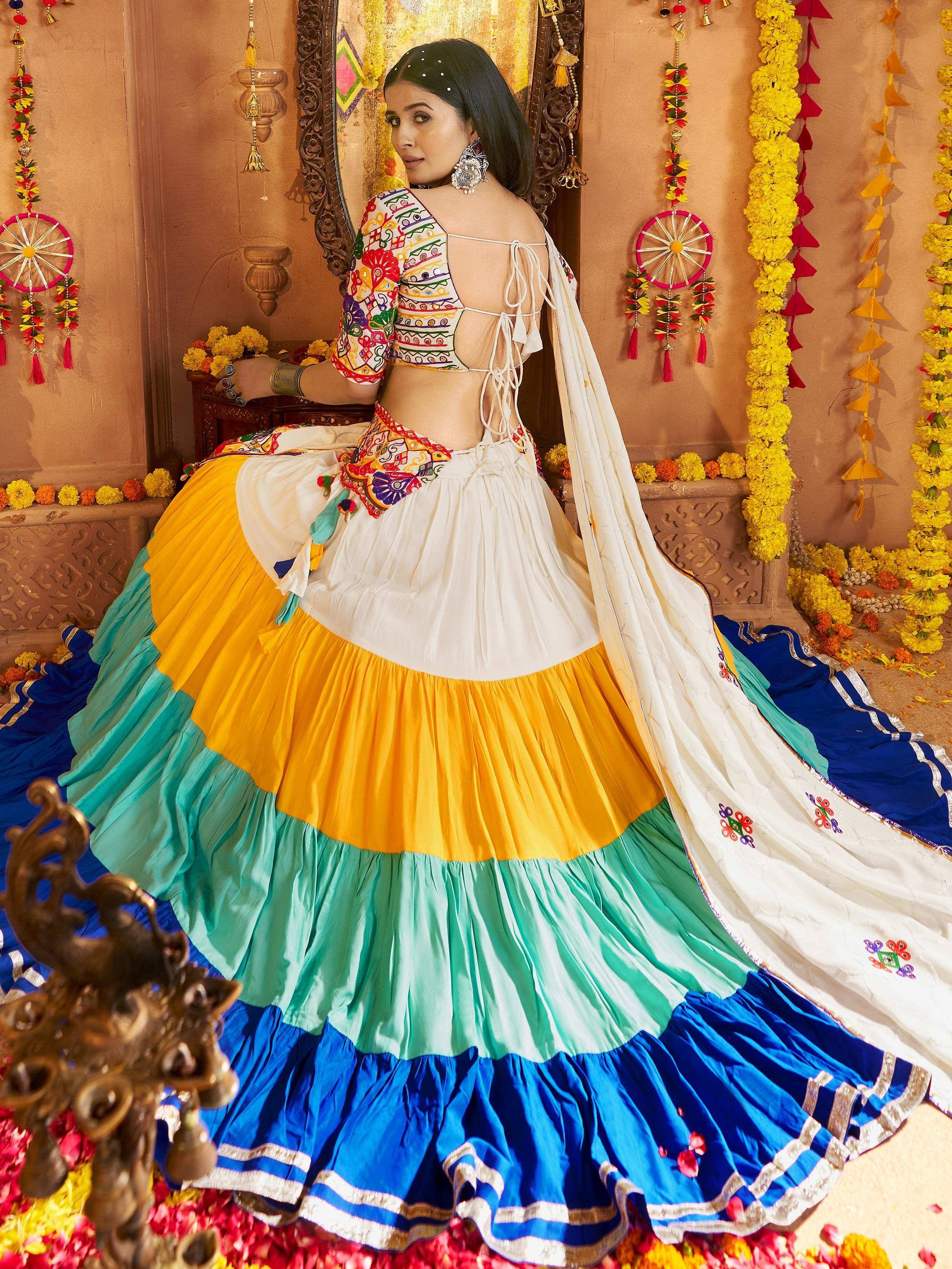 Colorful Indian lehenga choli with embroidered top, tiered skirt in yellow, green, blue, and white dupatta, festive decor