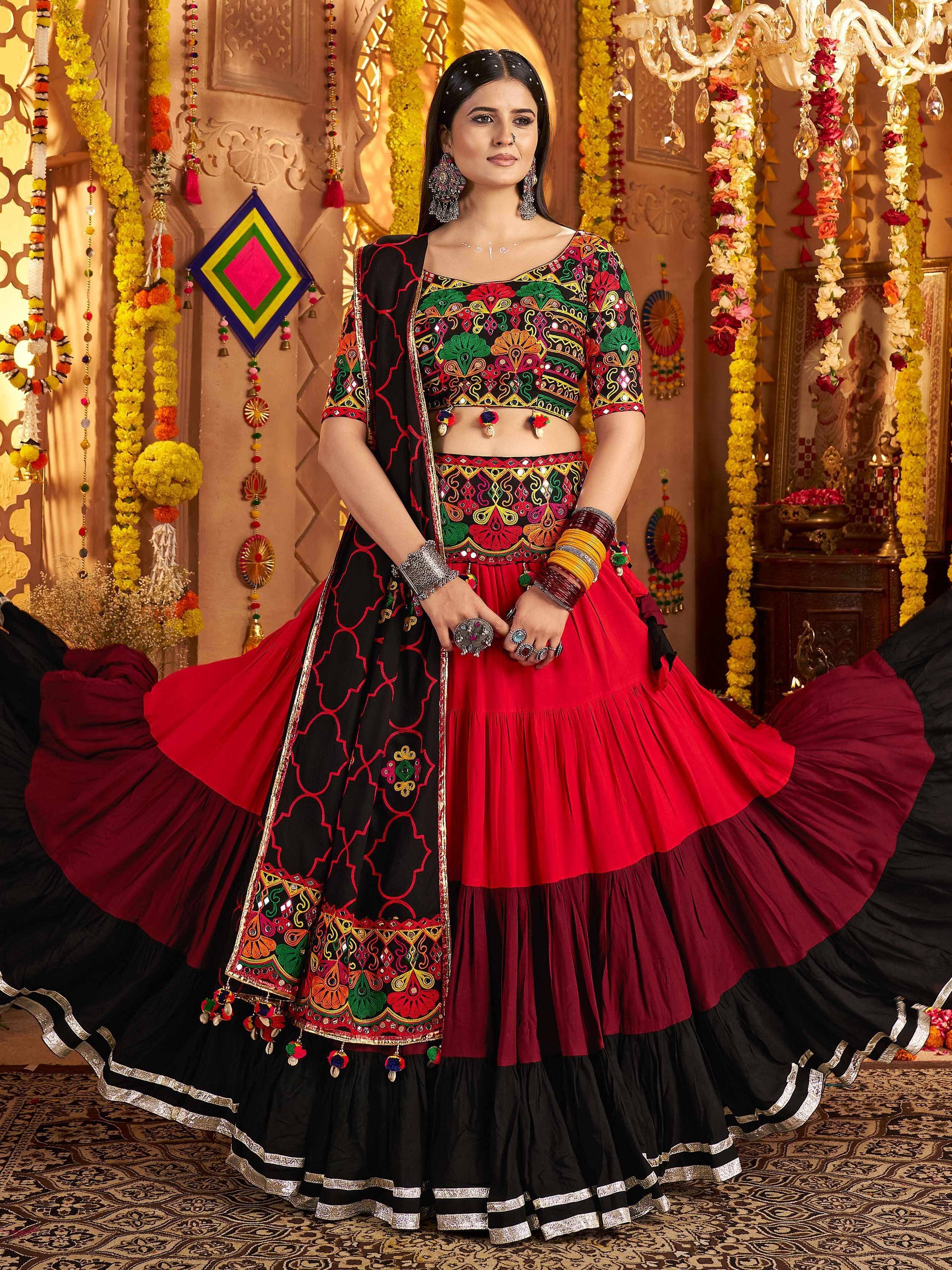 Woman in vibrant red and black embroidered lehenga choli with mirror work, perfect for Indian ethnic occasions.