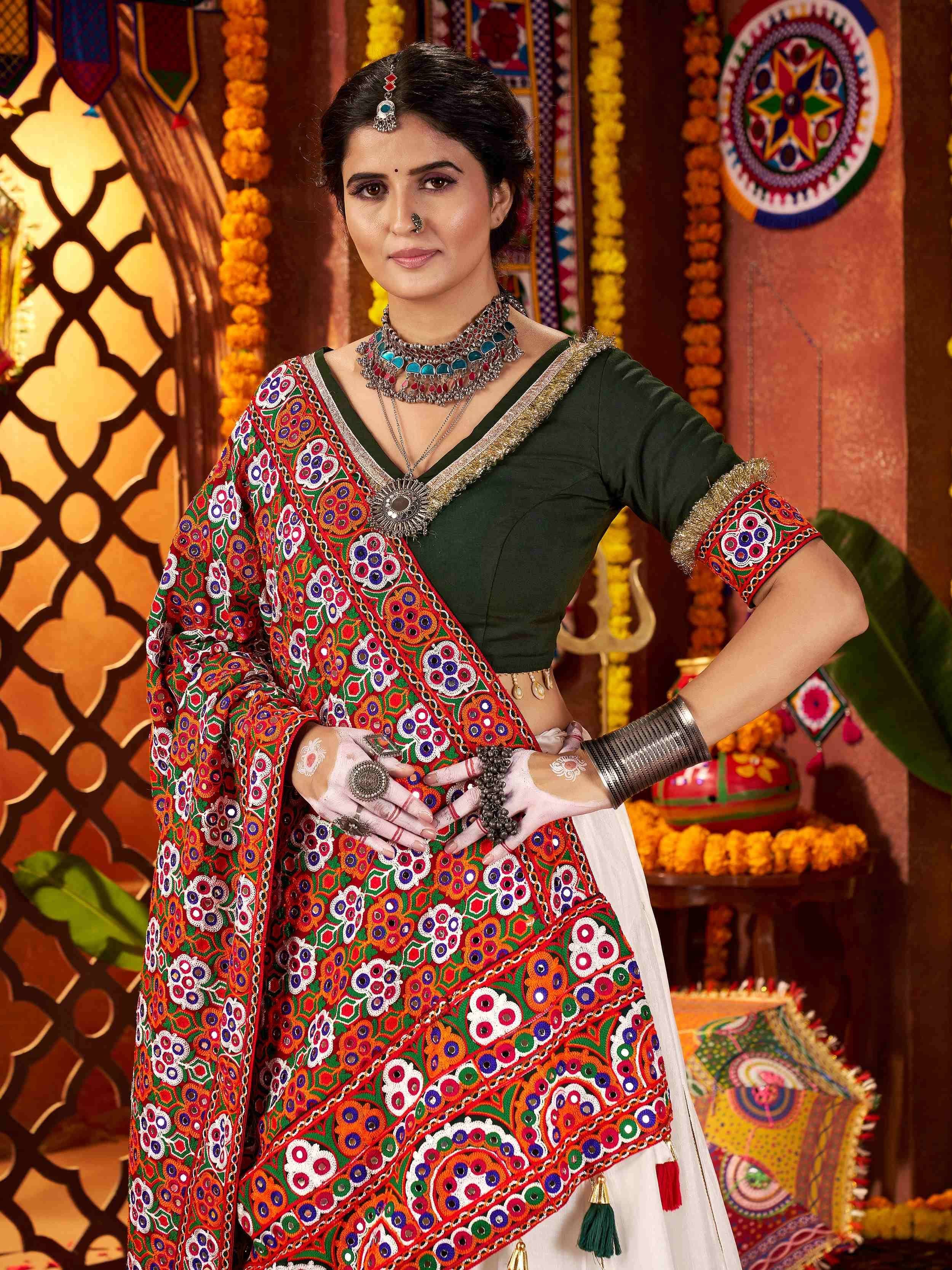 Woman in vibrant Indian ethnic wear with mirror work, traditional jewelry, and festive backdrop
