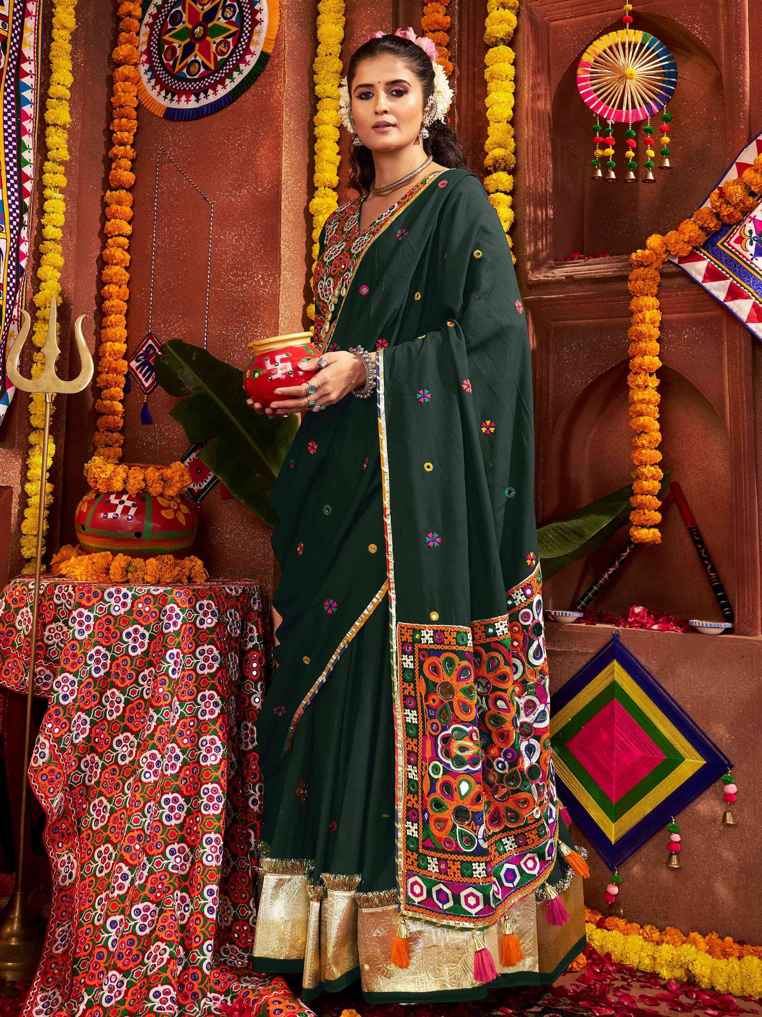 Green embroidered saree with colorful mirror work, festive marigold decor, and traditional Indian motifs