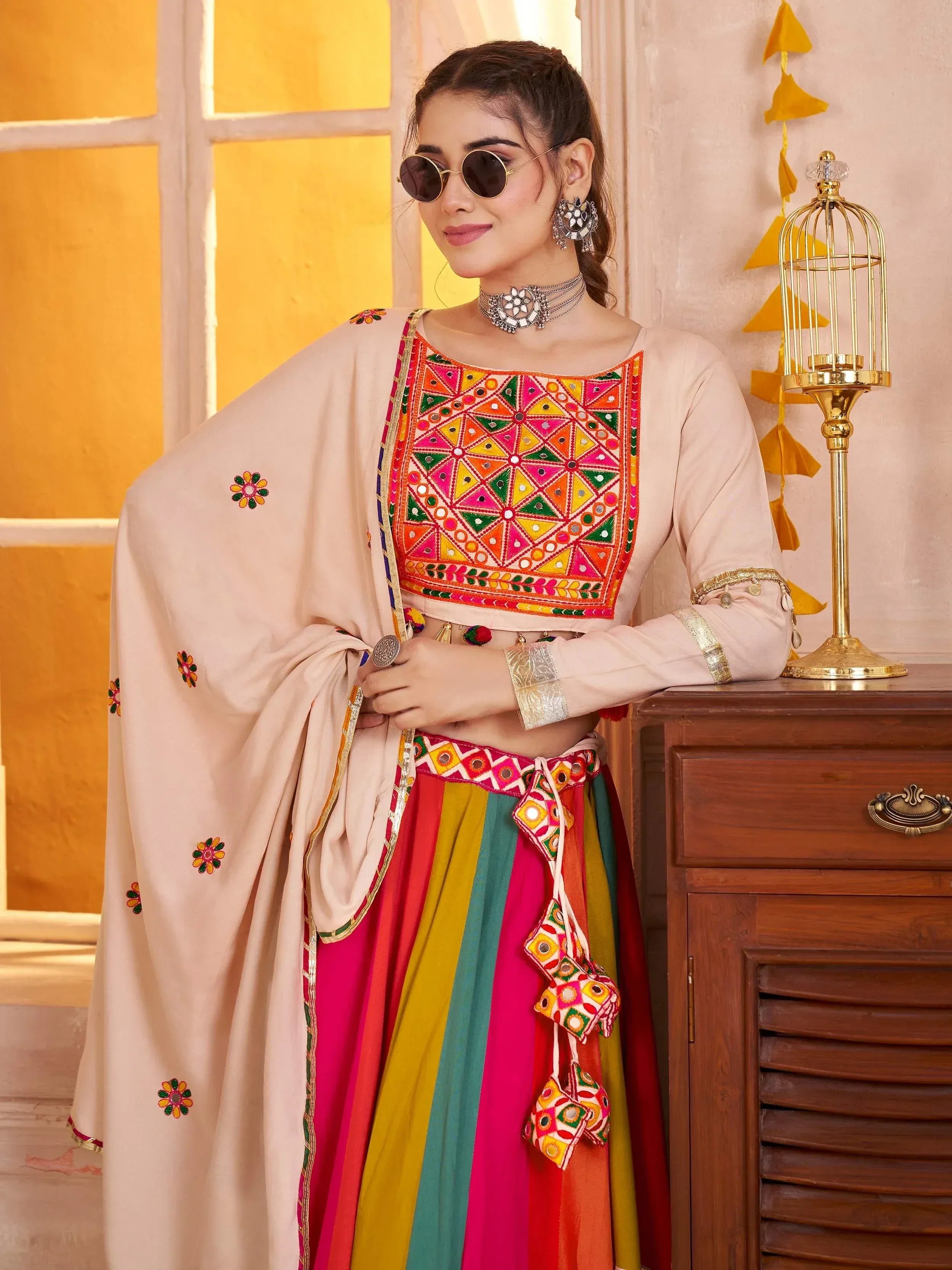Woman in colorful Indian ethnic wear with mirror work, floral dupatta, and vibrant striped skirt