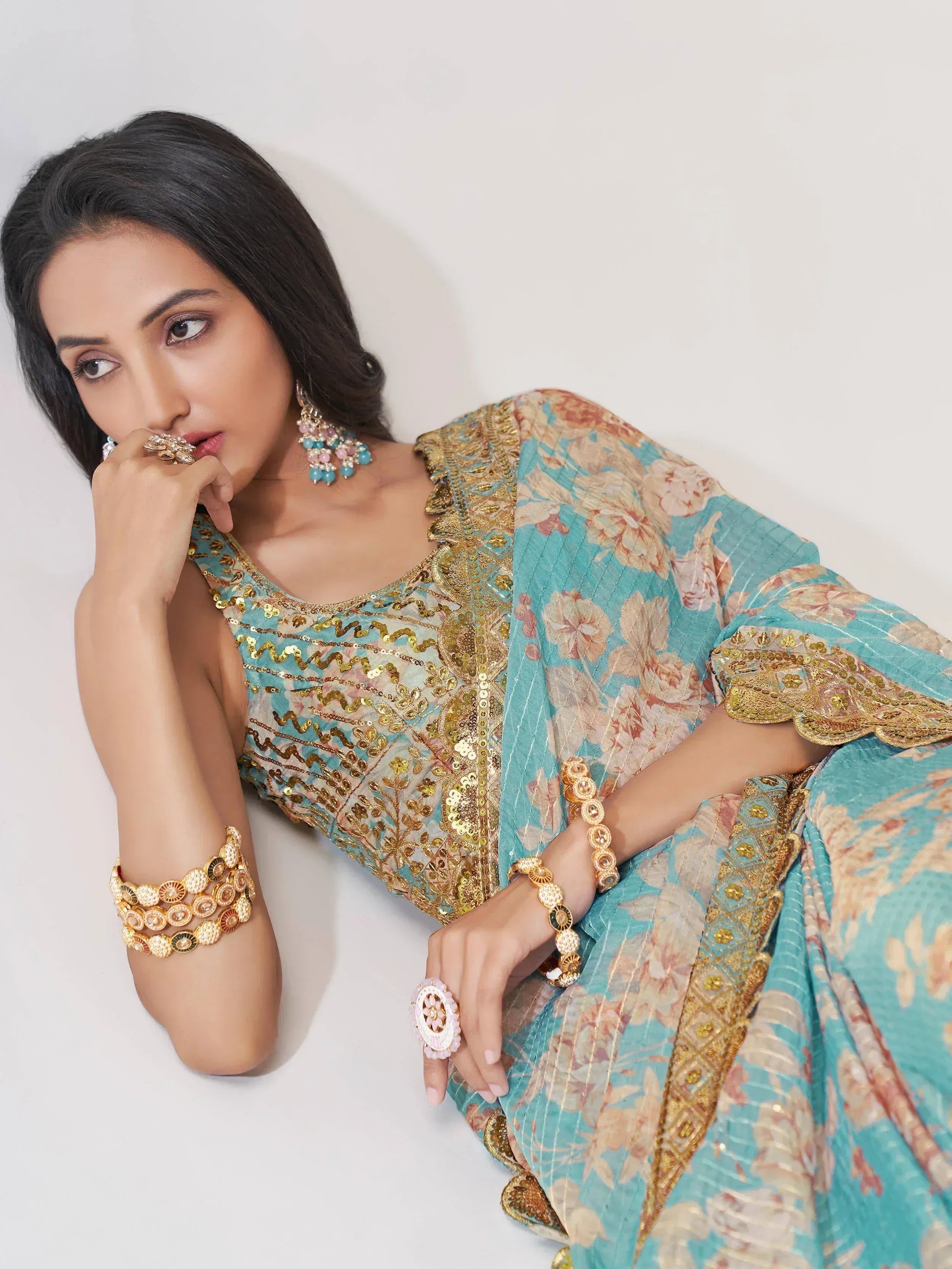 Woman in turquoise floral ethnic gown with gold embroidery and statement jewelry