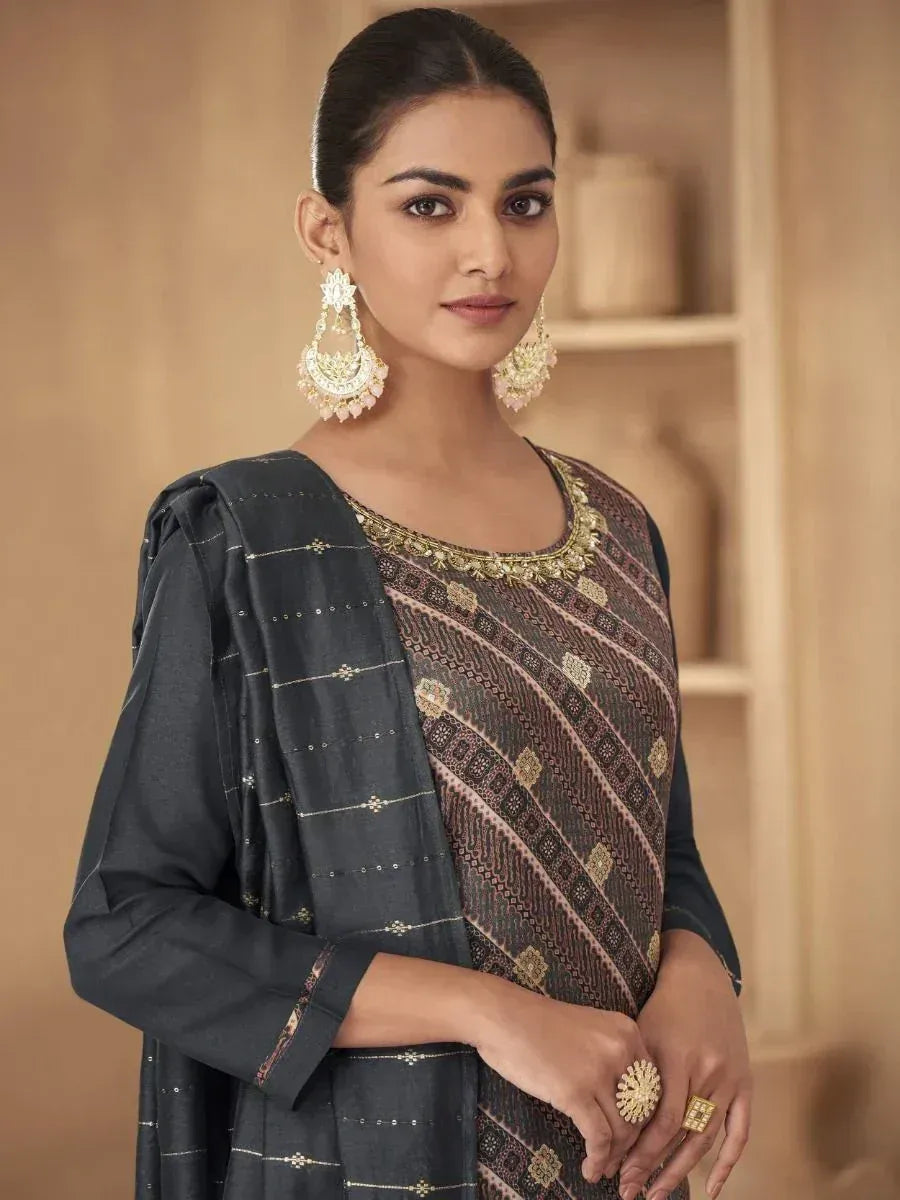 Woman in elegant ethnic salwar kameez with gold embroidery and matching dupatta, styled with traditional jhumka earrings.