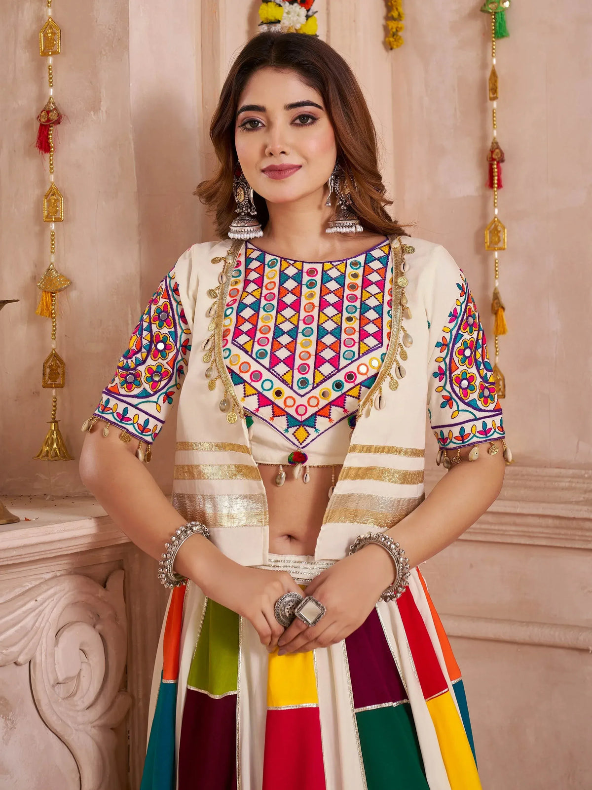 Woman in colorful embroidered Indian ethnic wear with mirror work and gold detailing, perfect for festive occasions.