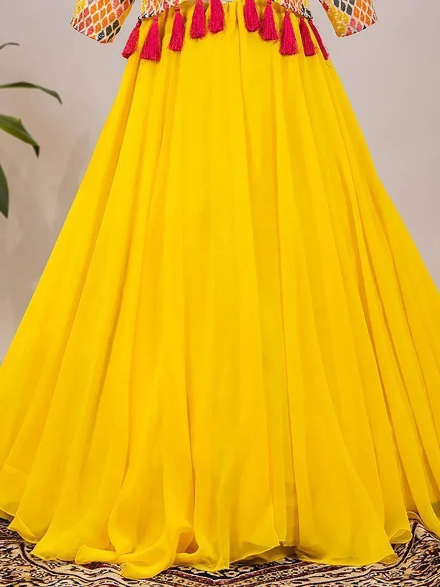 Vibrant yellow ethnic gown with pink tassels, perfect for festive occasions and Indian celebrations.