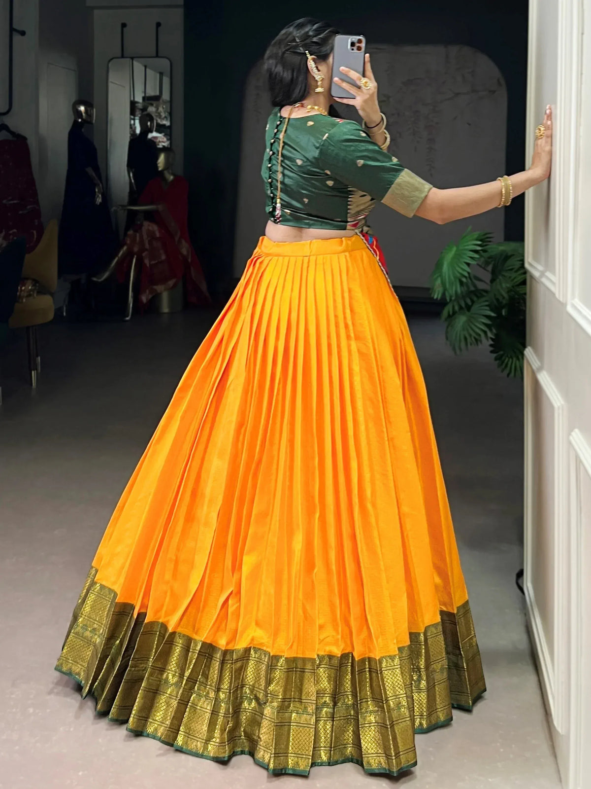 Vibrant orange pleated lehenga with green blouse and golden border, perfect for Indian ethnic wear