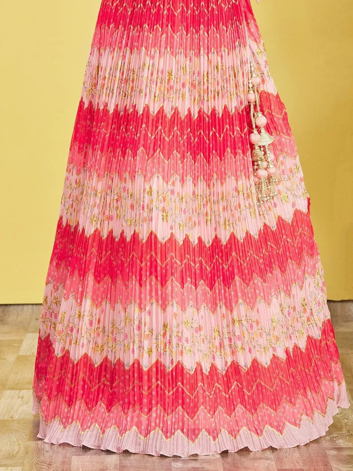 Pink and red pleated lehenga skirt with gold embroidery and tassels, ideal for Indian ethnic wear
