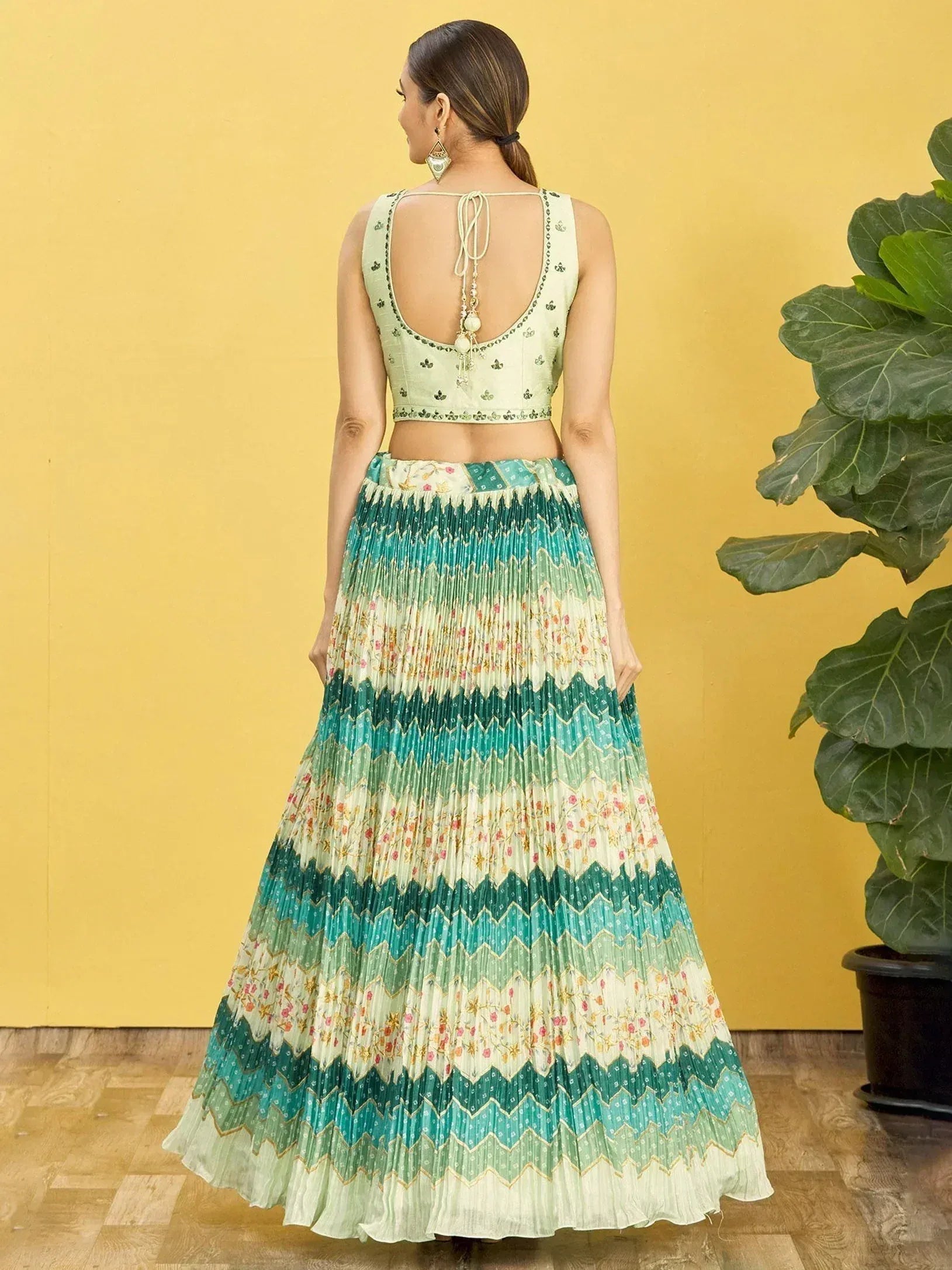 Back view of woman in green floral pleated lehenga choli with open back blouse, ethnic wear