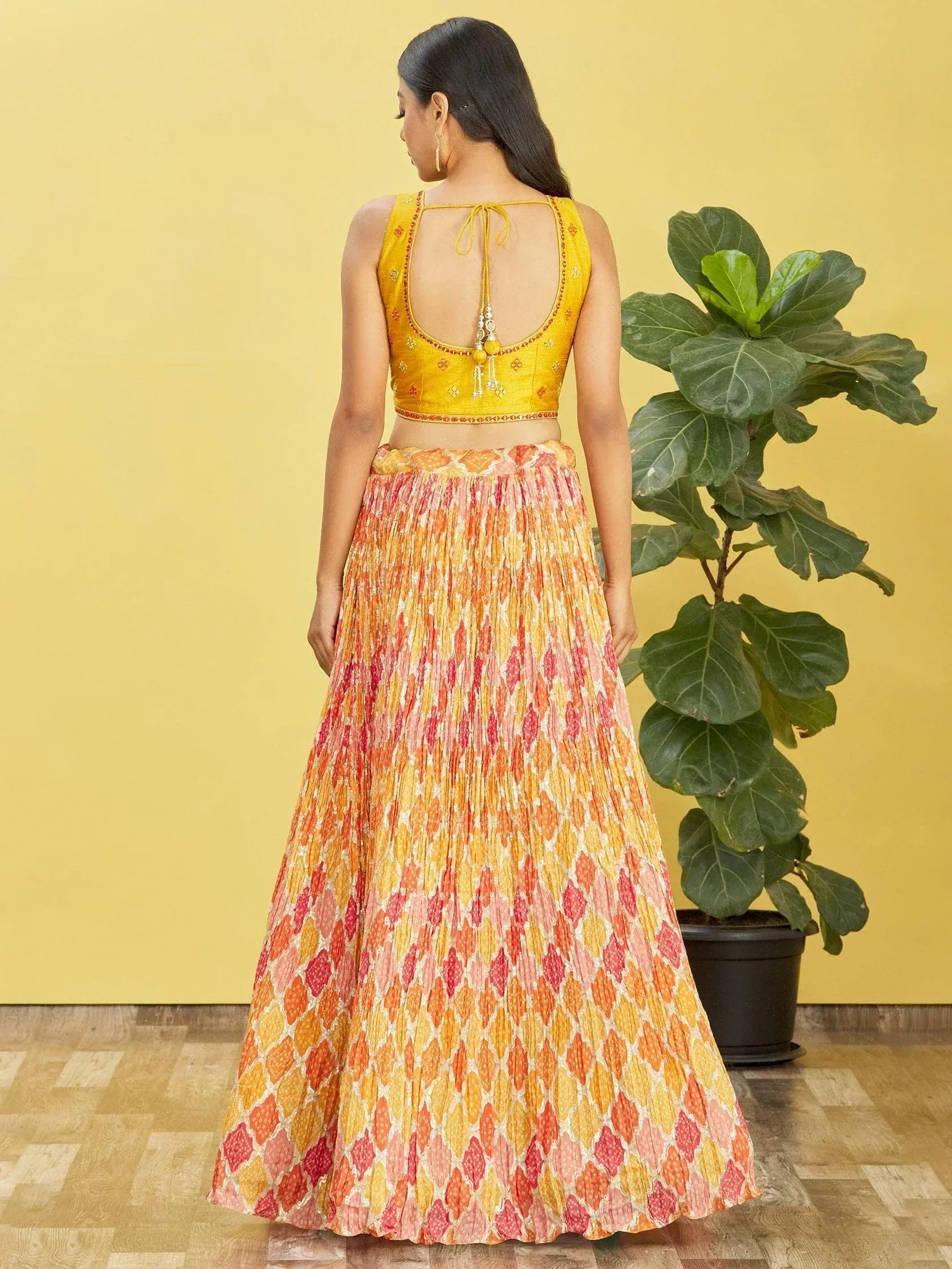 Yellow embroidered lehenga choli with orange pink printed skirt, back view