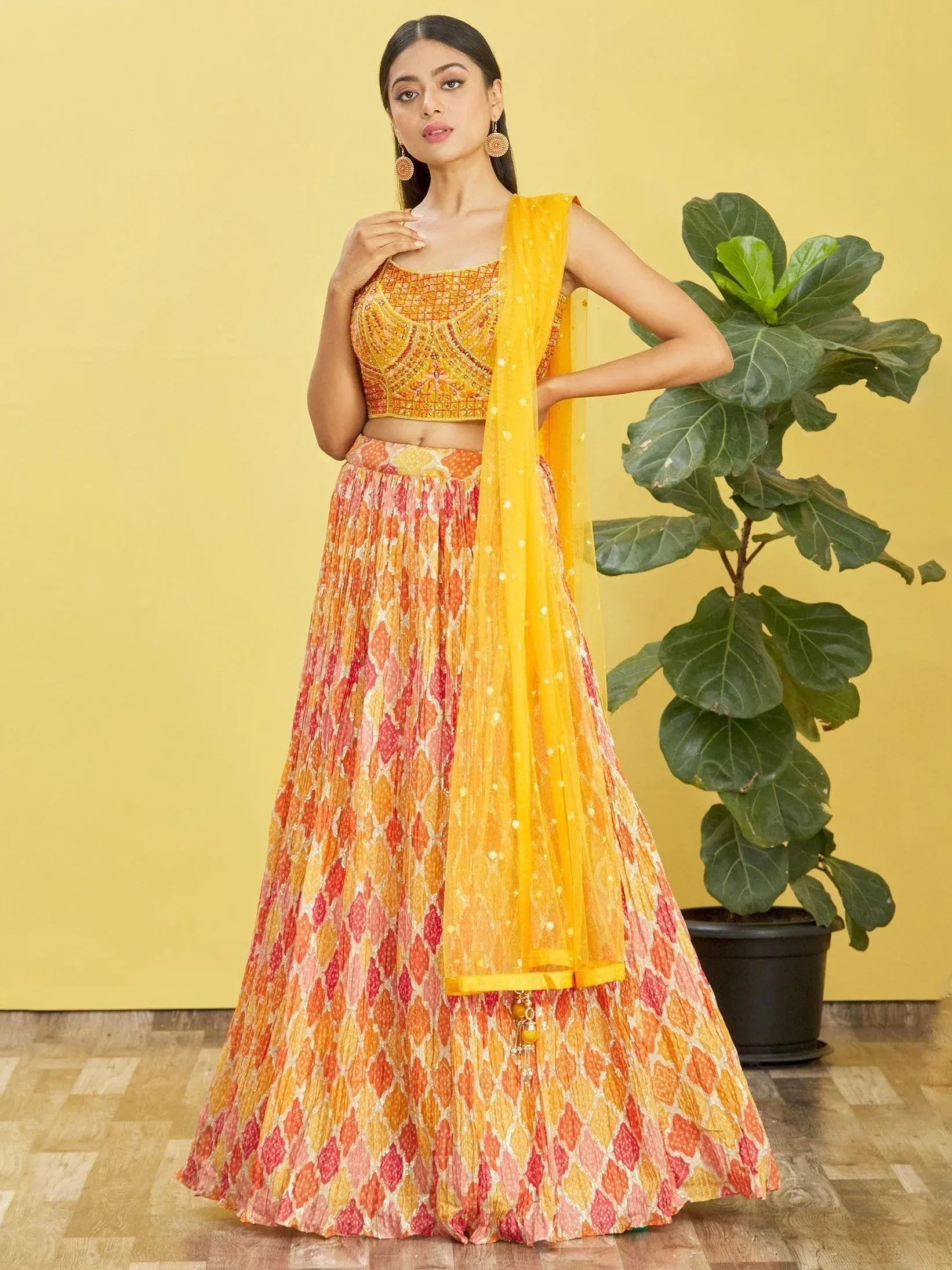 Vibrant orange and yellow printed lehenga choli with embellished blouse and sheer dupatta, perfect for Indian ethnic occasions.