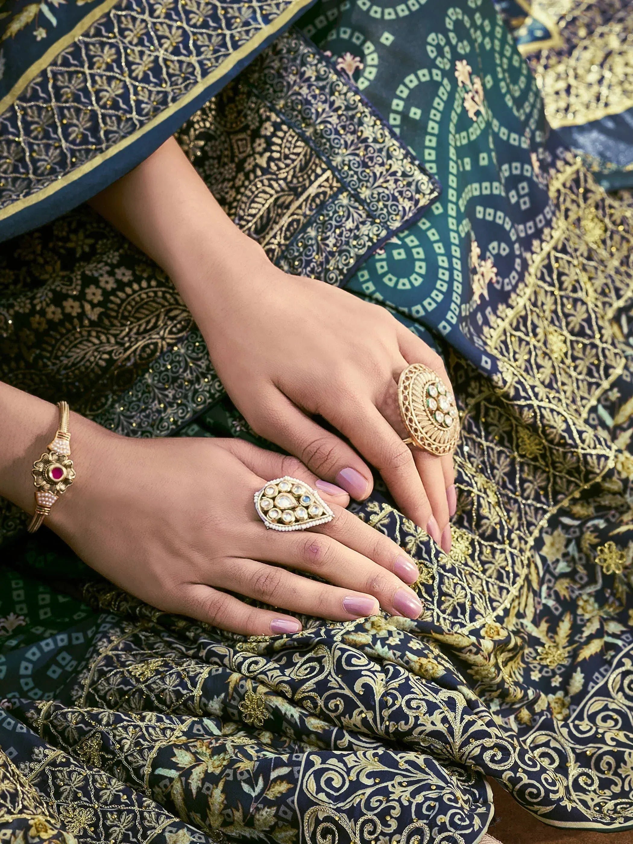 Elegant Indian ethnic wear with intricate gold embroidery, paired with traditional kundan rings and bracelet.