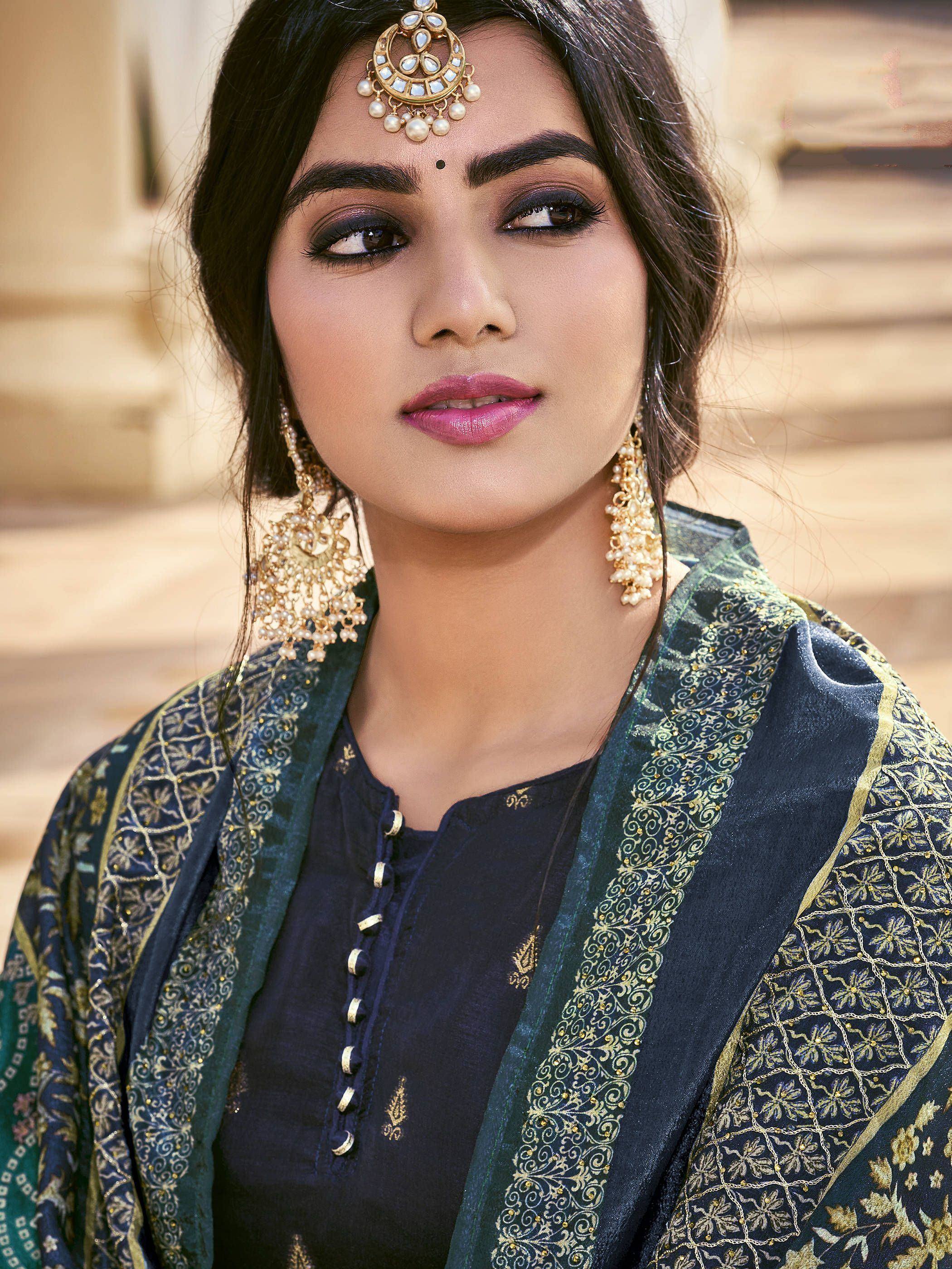 Woman in elegant Indian ethnic wear with gold embroidery, matching dupatta, and traditional jewelry.