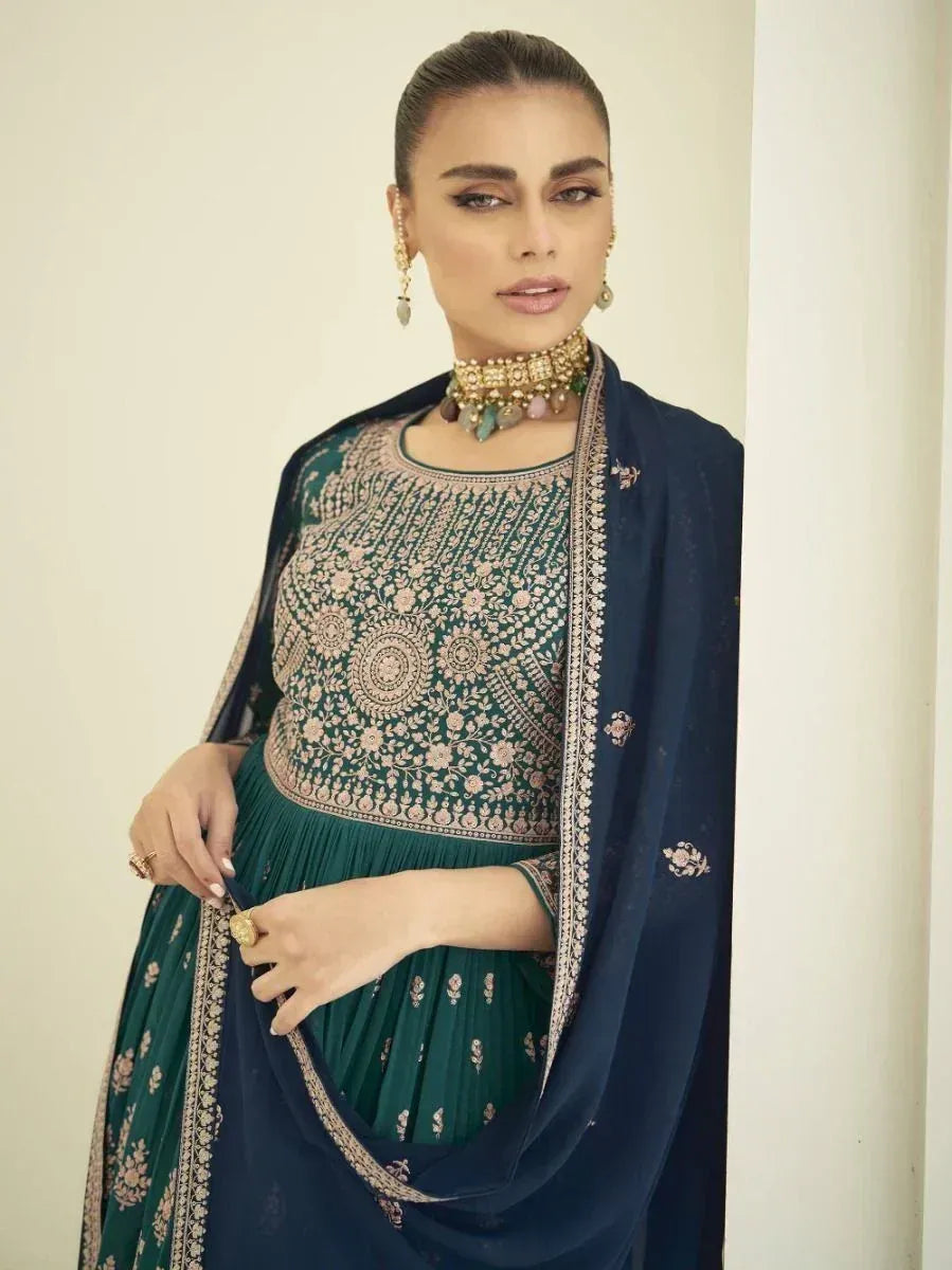 Woman wearing an embroidered green and navy blue ethnic gown with dupatta and jewelry