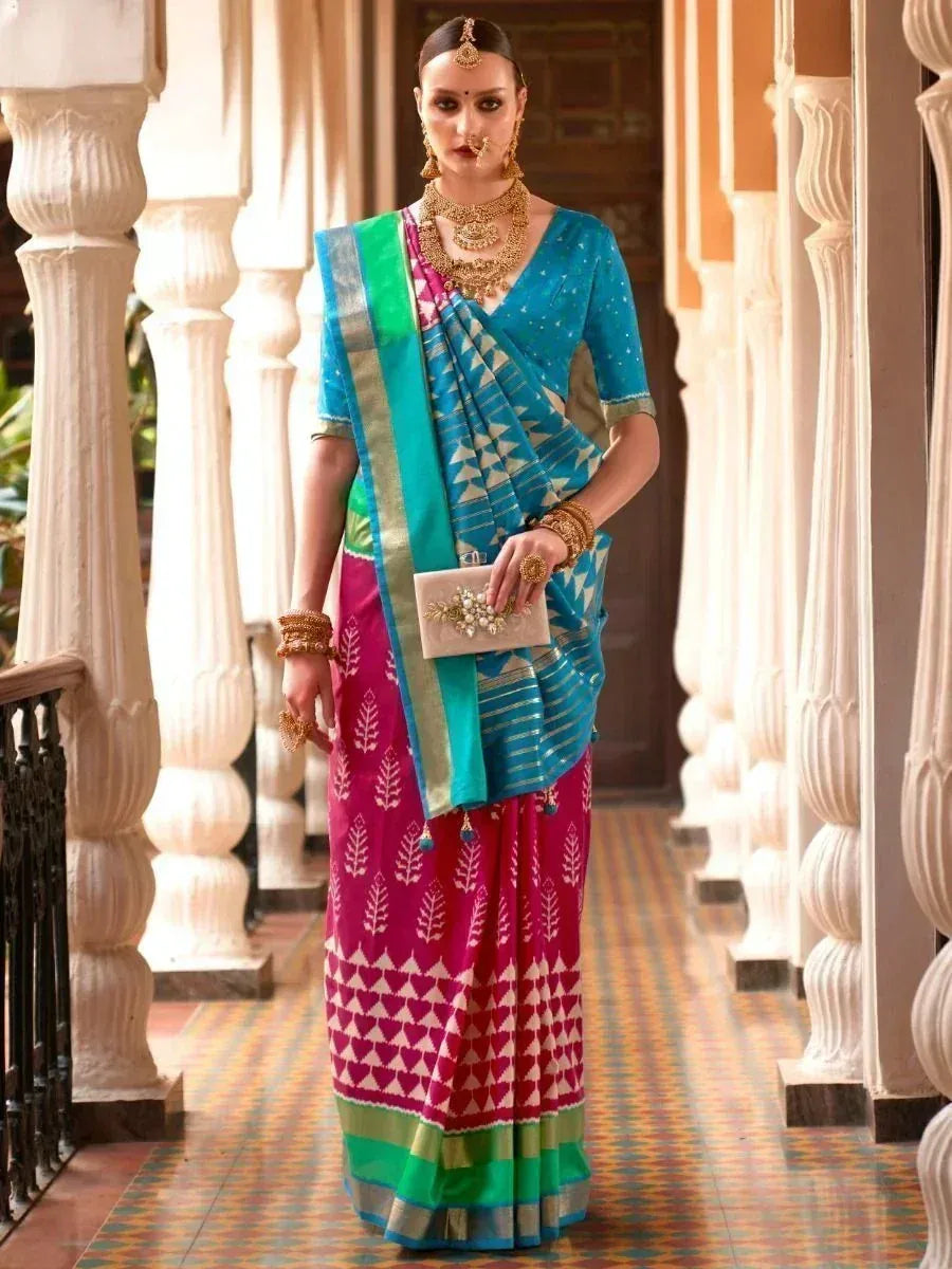 Woman in vibrant blue and pink printed saree with gold jewelry, traditional Indian ethnic wear