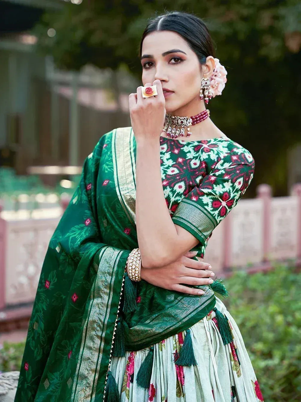 Woman in green floral lehenga choli with gold border and tassels, traditional Indian ethnic wear