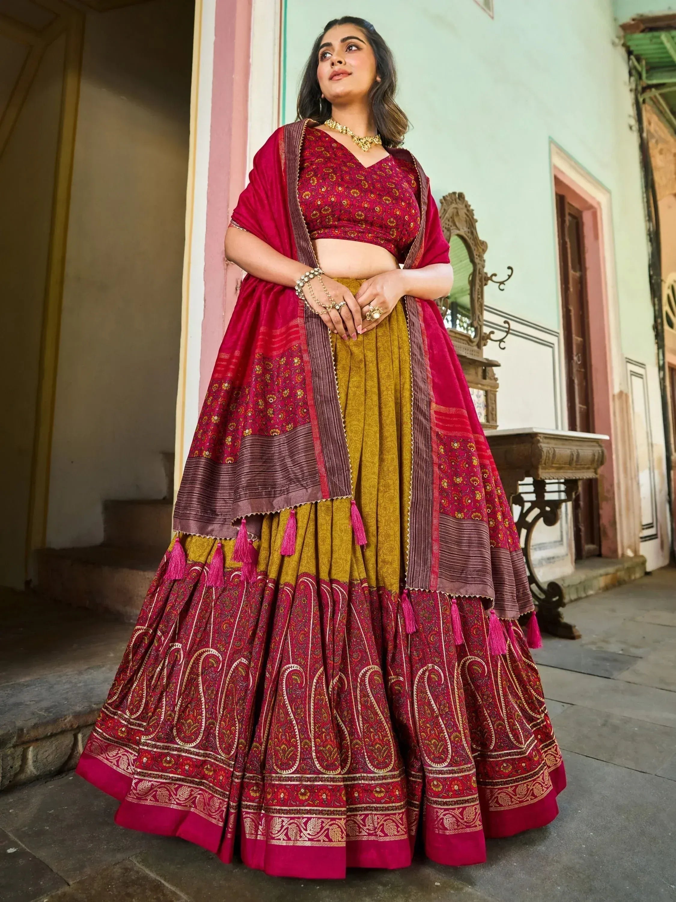 Woman in maroon and mustard designer lehenga choli with floral and paisley prints, perfect for Indian ethnic occasions