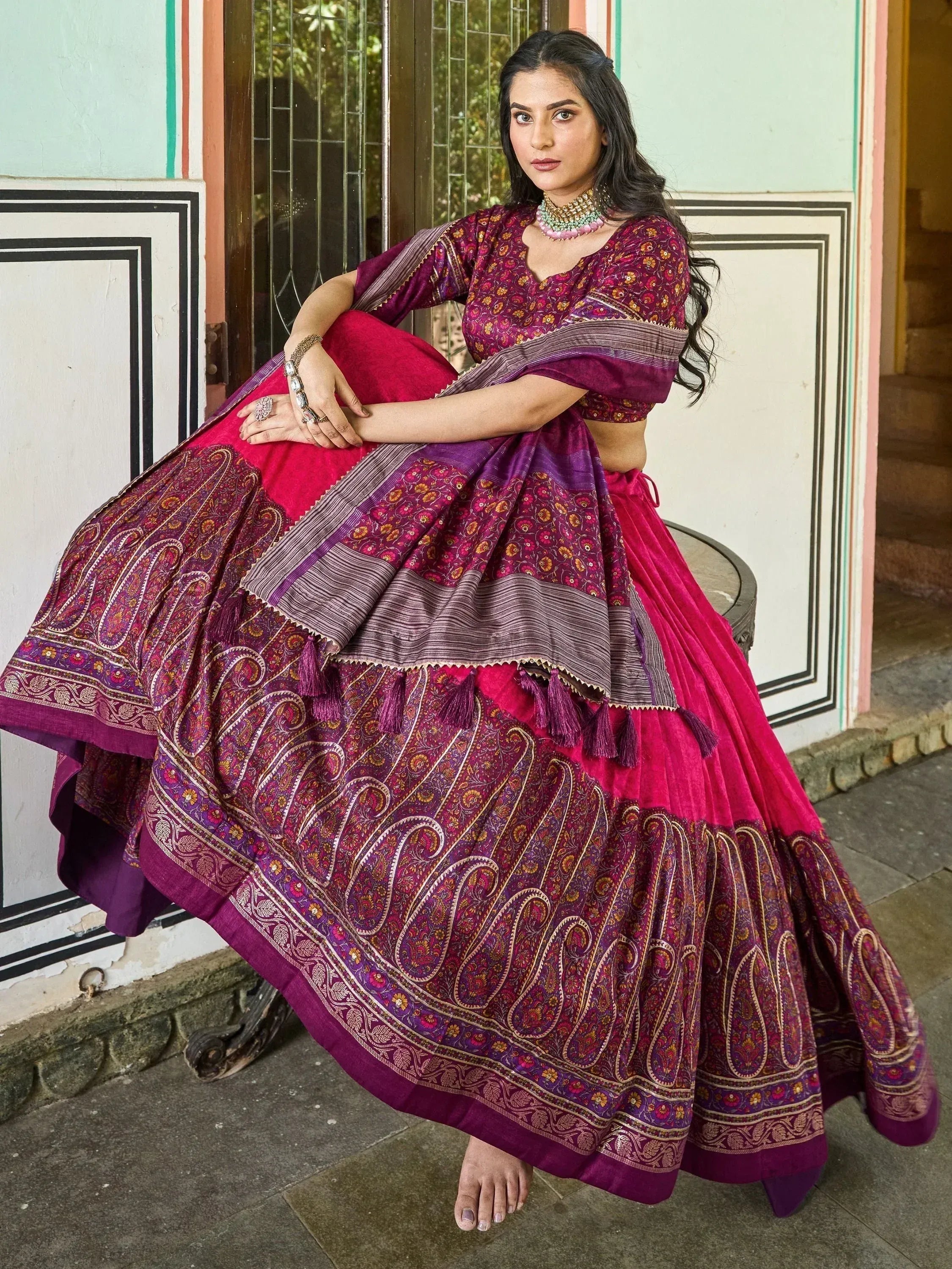 Woman in vibrant purple and pink printed lehenga choli with tassels, perfect for Indian ethnic occasions