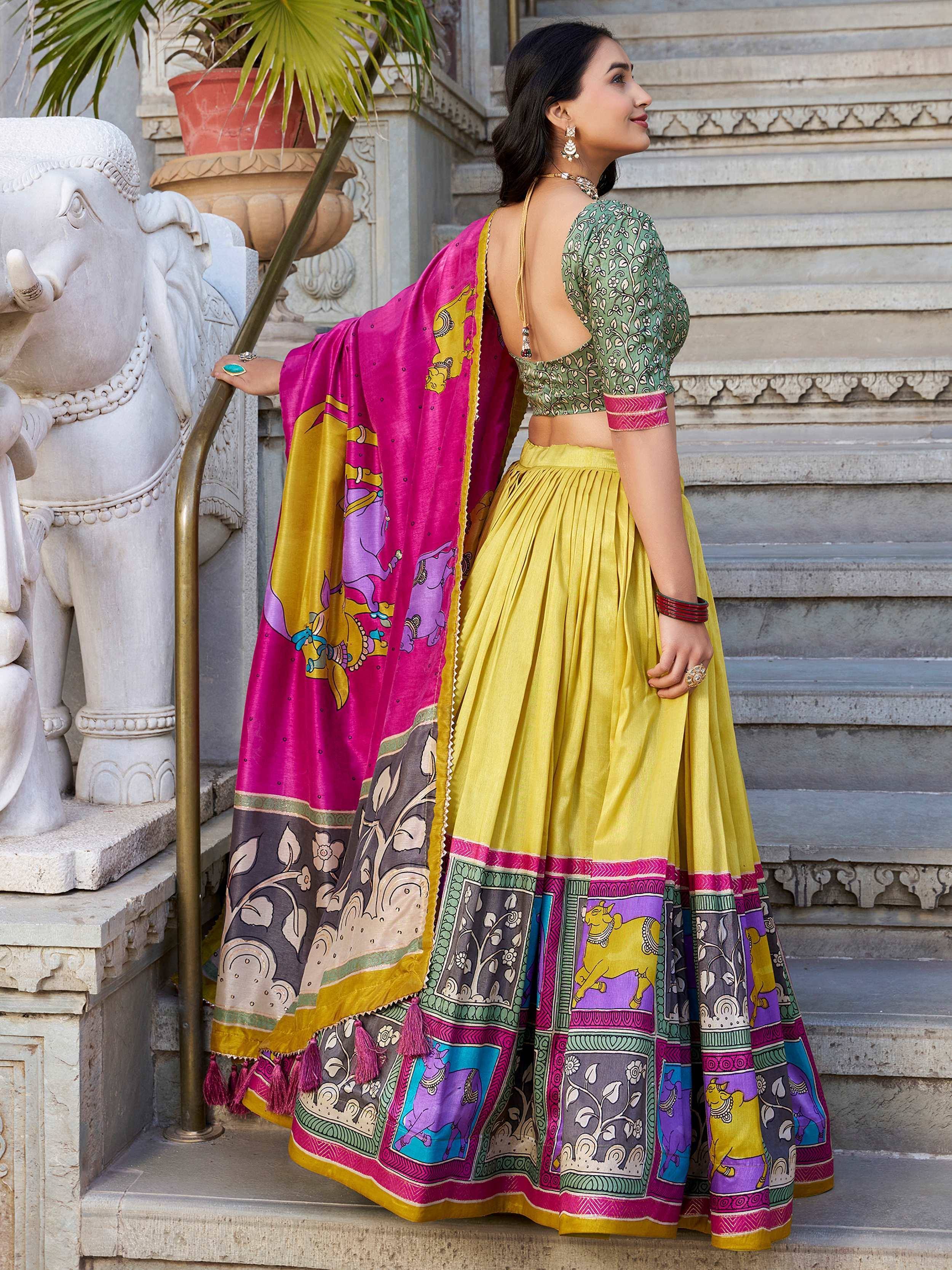 Woman in vibrant yellow lehenga choli with pink dupatta, featuring elephant and floral prints, perfect for Indian ethnic wear.